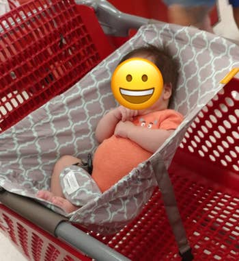 A baby in the hammock attached to a shopping cart