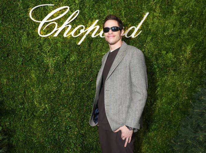 A close-up of Pete standing in front of a grass wall that says Chopard at a red carpet event