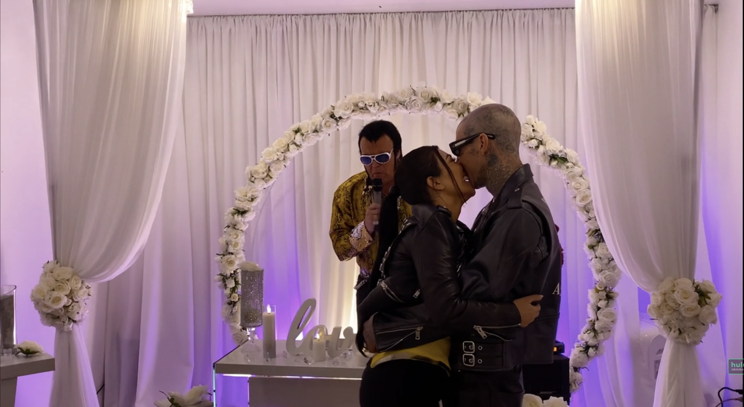 Kourtney and Travis kissing in front of "Elvis"