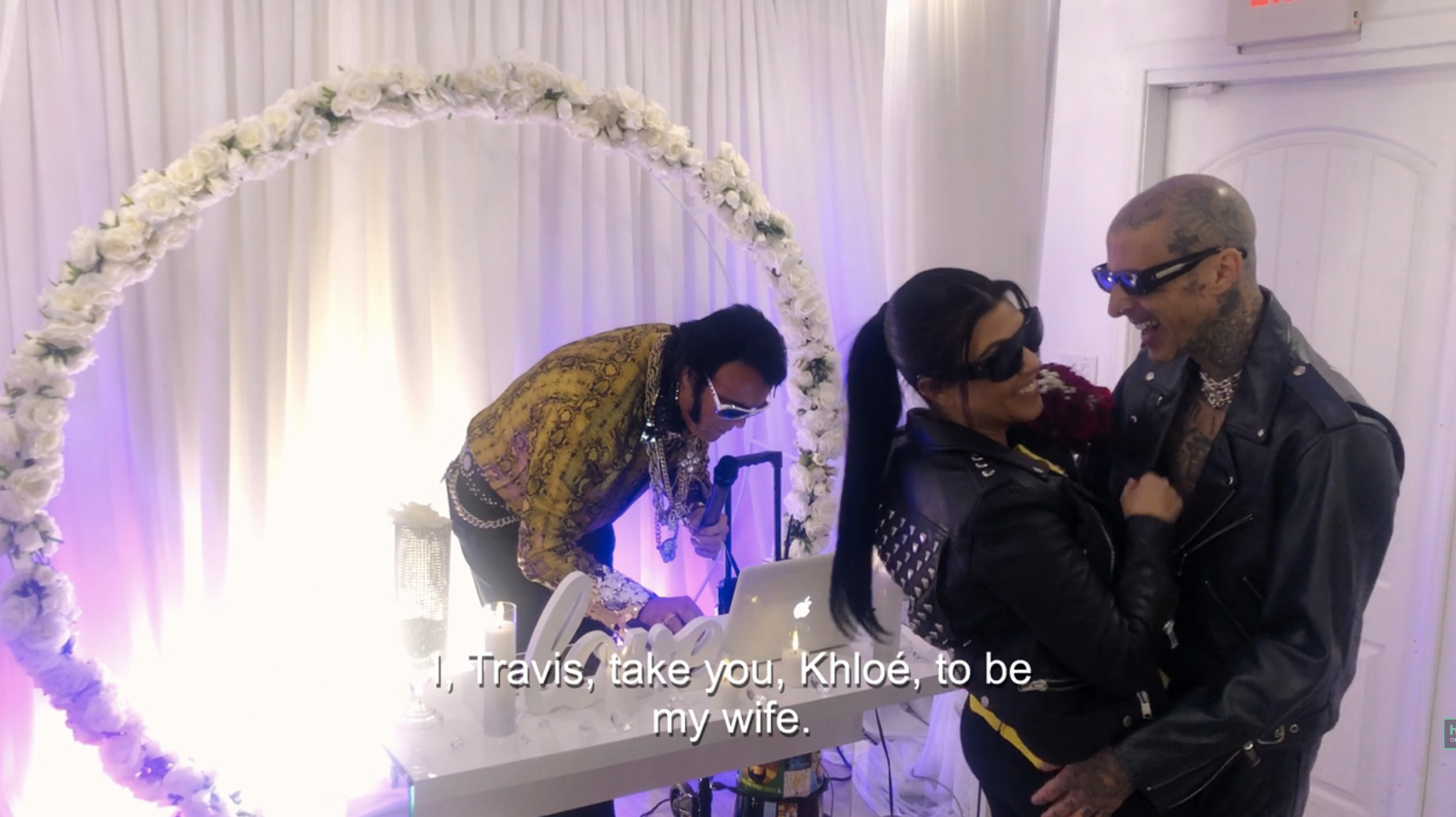 Kourtney and Travis laughing in front of "Elvis" with the caption, "I, Travis, take you, Khloé, to be my wife"