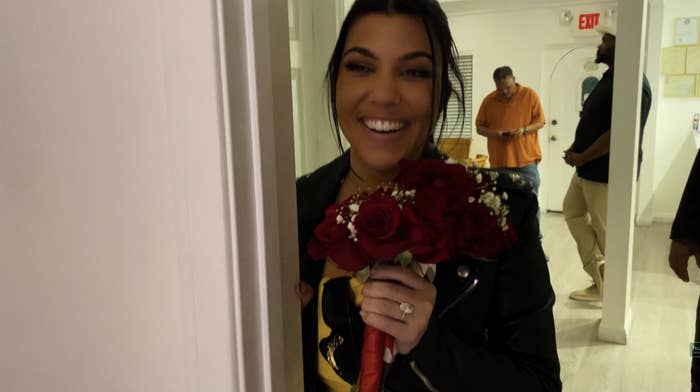 Kourtney smiling and holding a bouquet