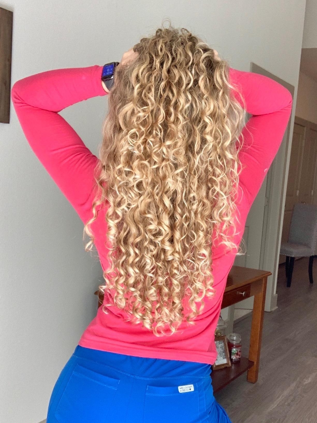 back view of reviewer&#x27;s defined blonde curly hair after using the heat and humidity gel