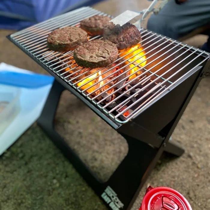 The portable grill in use with four burgers
