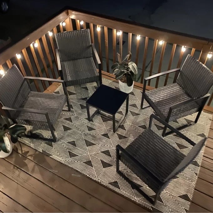a reviewer picture of the rug on a deck with patio furniture on it