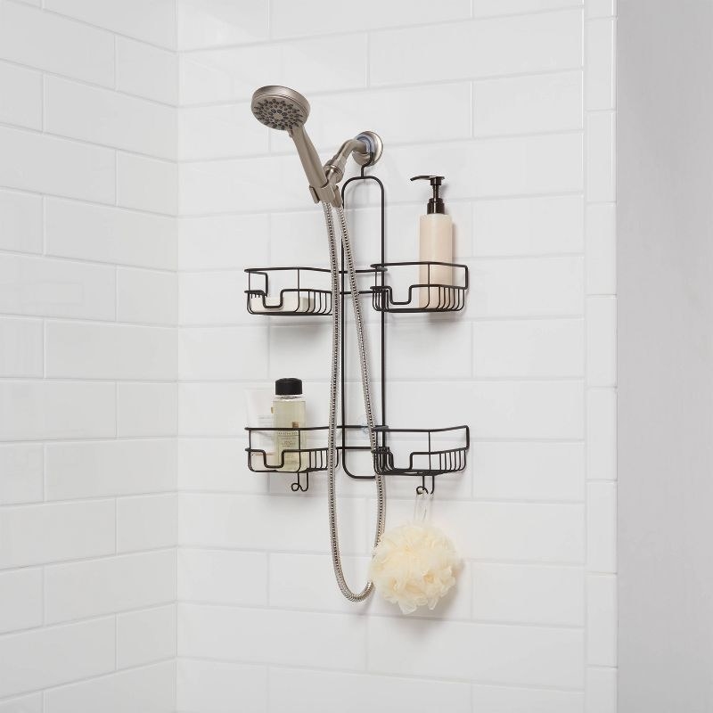 a black shower caddy hanging holding shampoos and a loufa over a shower head