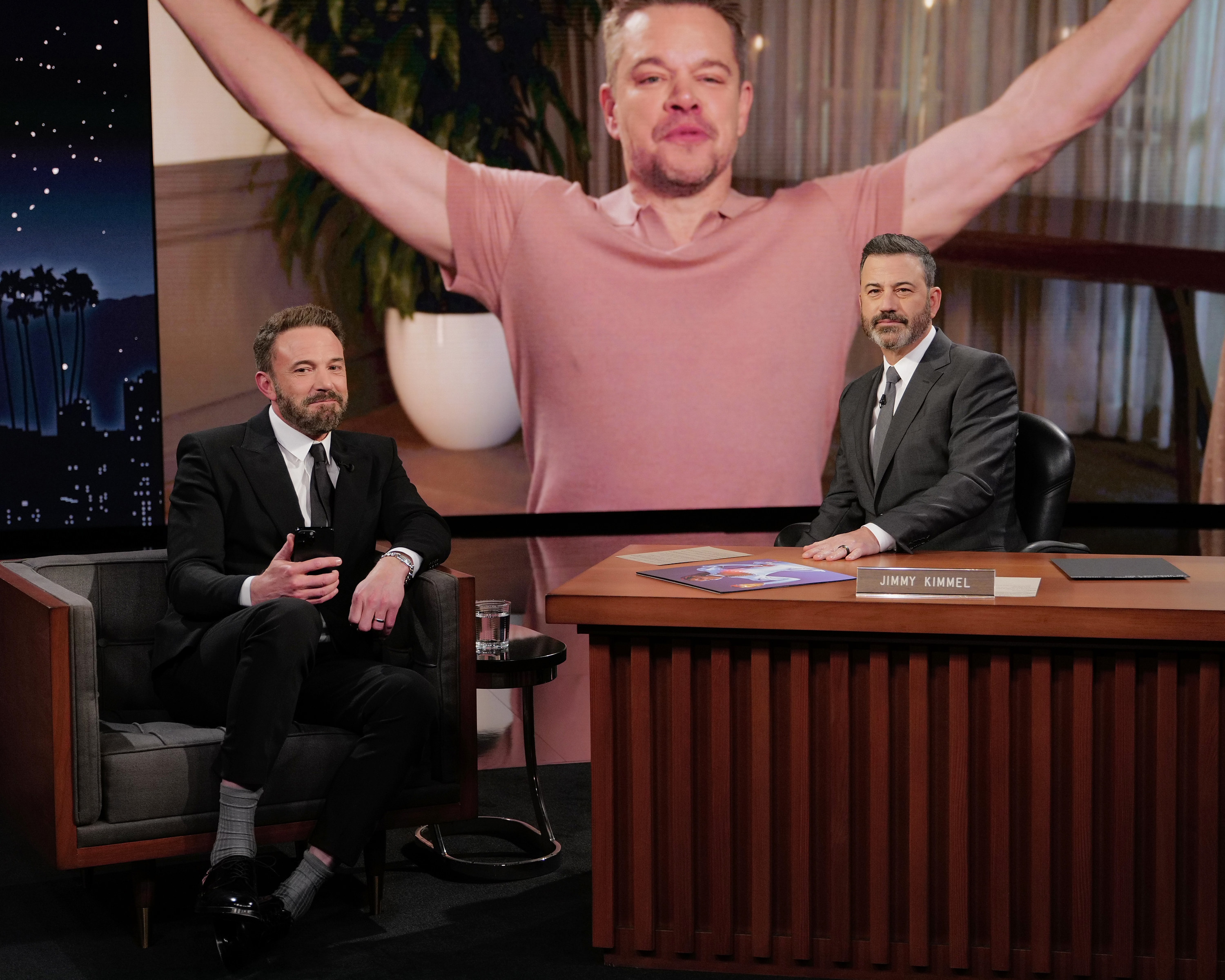ben and jimmy sitting in front of a screen with matt throwing his arms up in victory
