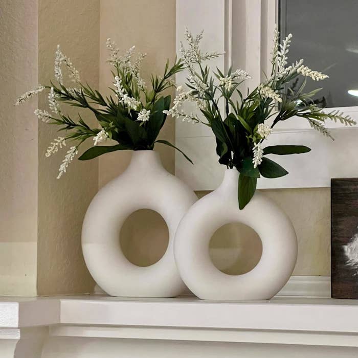 The vases on a mantle with flowers