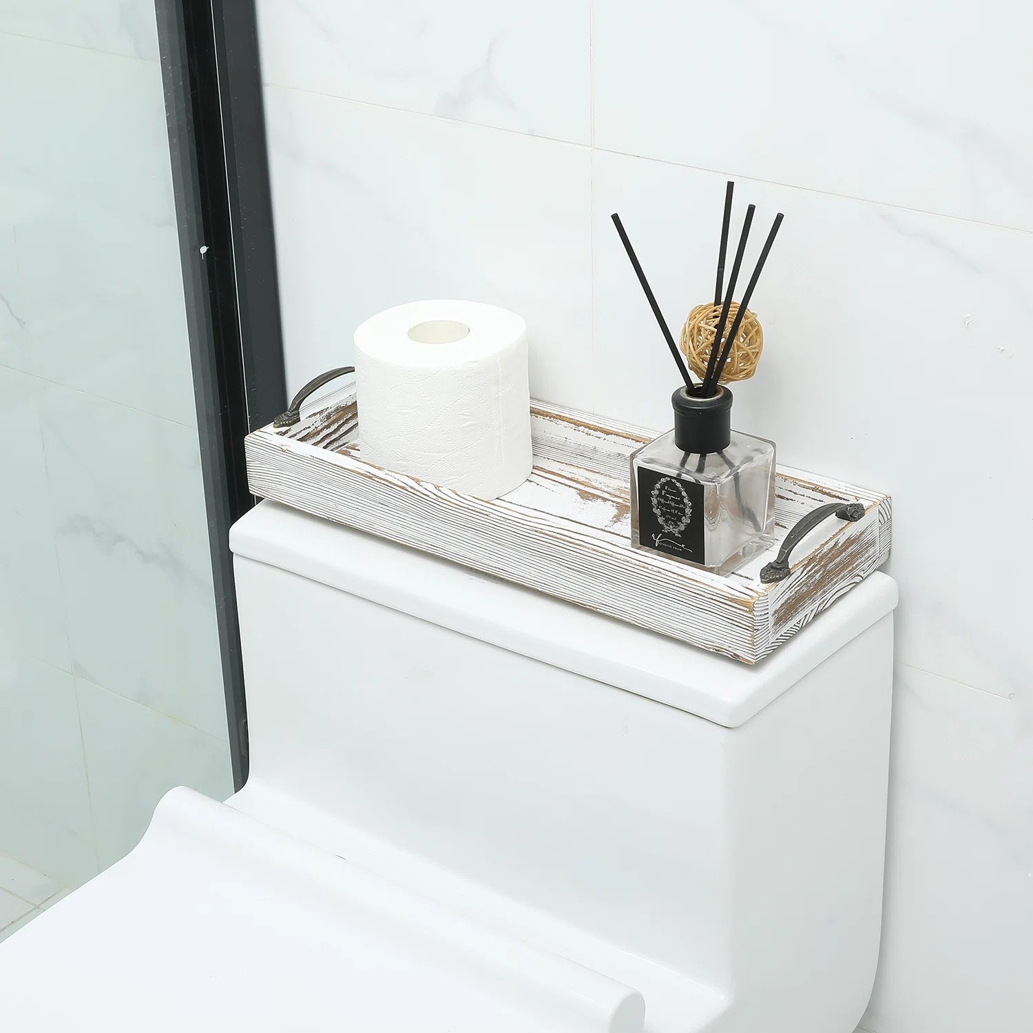 the tray holding toilet paper and a diffuser on the back of a toilet