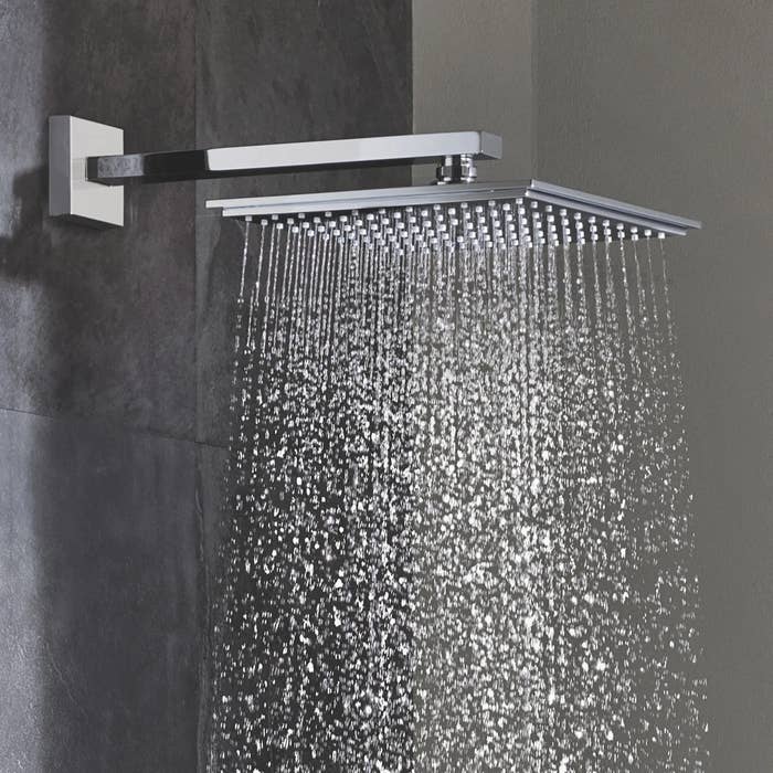 The square shower head spouting water in a shower
