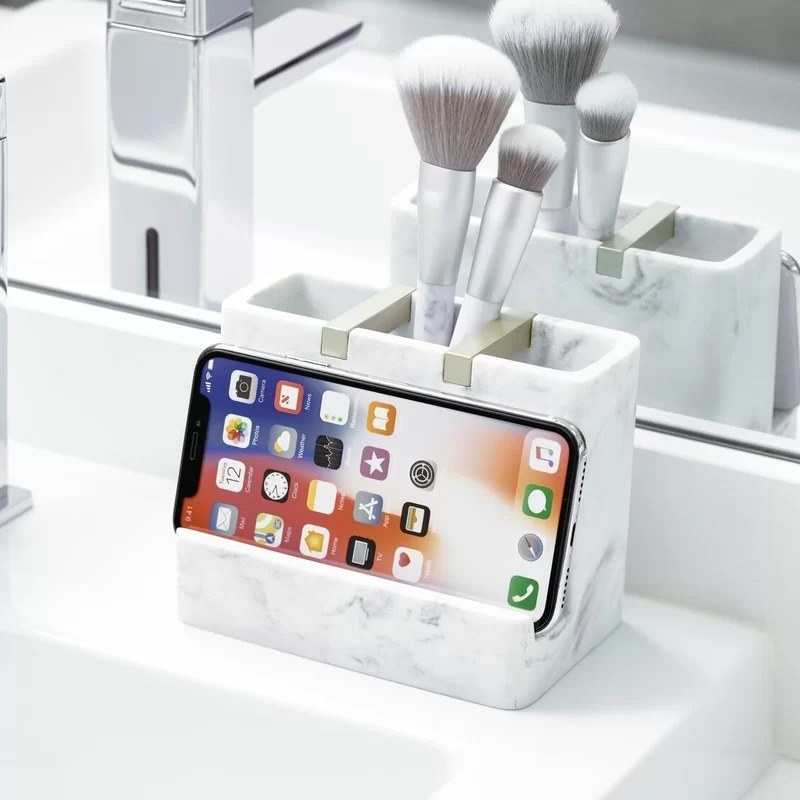 The bathroom organizer with three compartments and a phone holder on a sink ledge