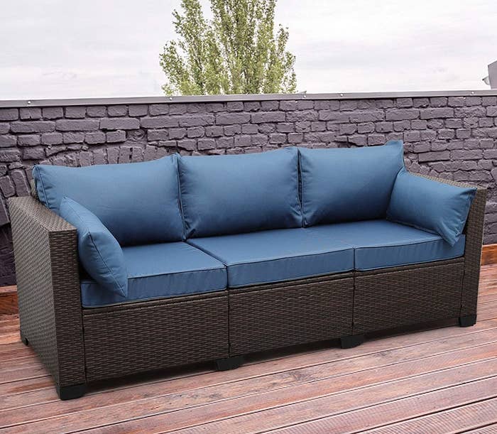 The blue sofa with a black frame is shown on a wood deck