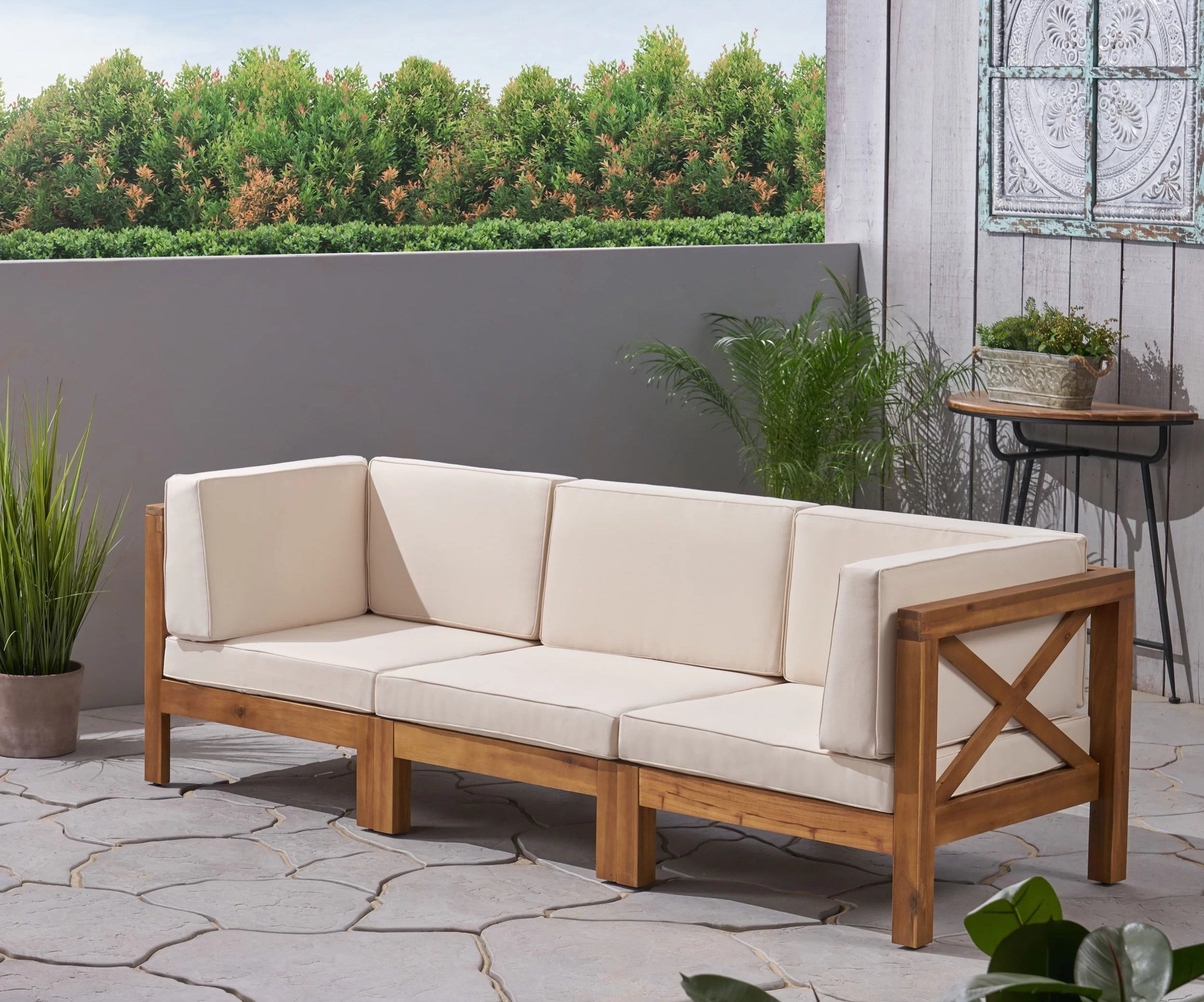 A wood sofa with beige cushions is shown on a patio