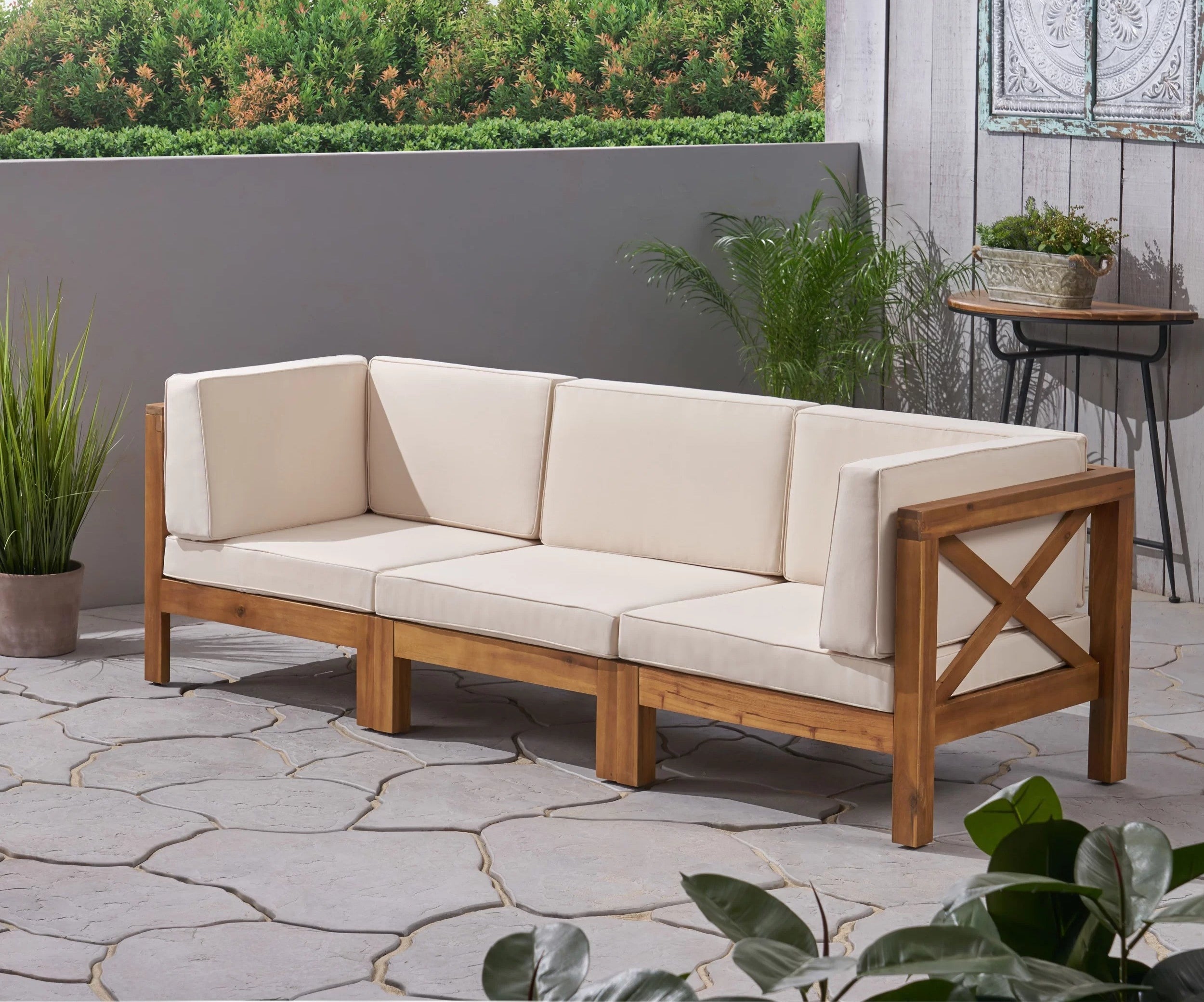 A wood sofa with beige cushions is shown on a patio