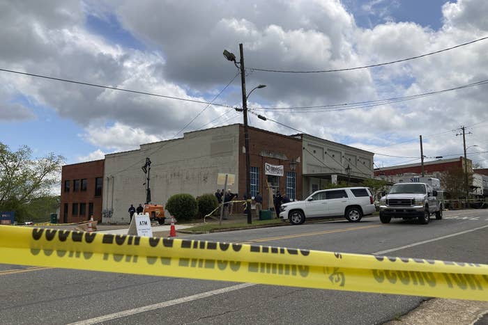 Cars in front of a low building behind a police barricade tape