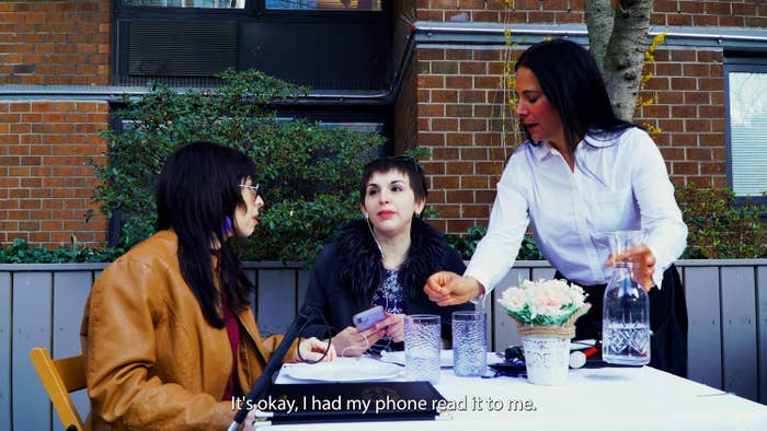 Logan, Amy (Bree Klauser) and the server (Josey Miler) are at an outdoor restaurant table