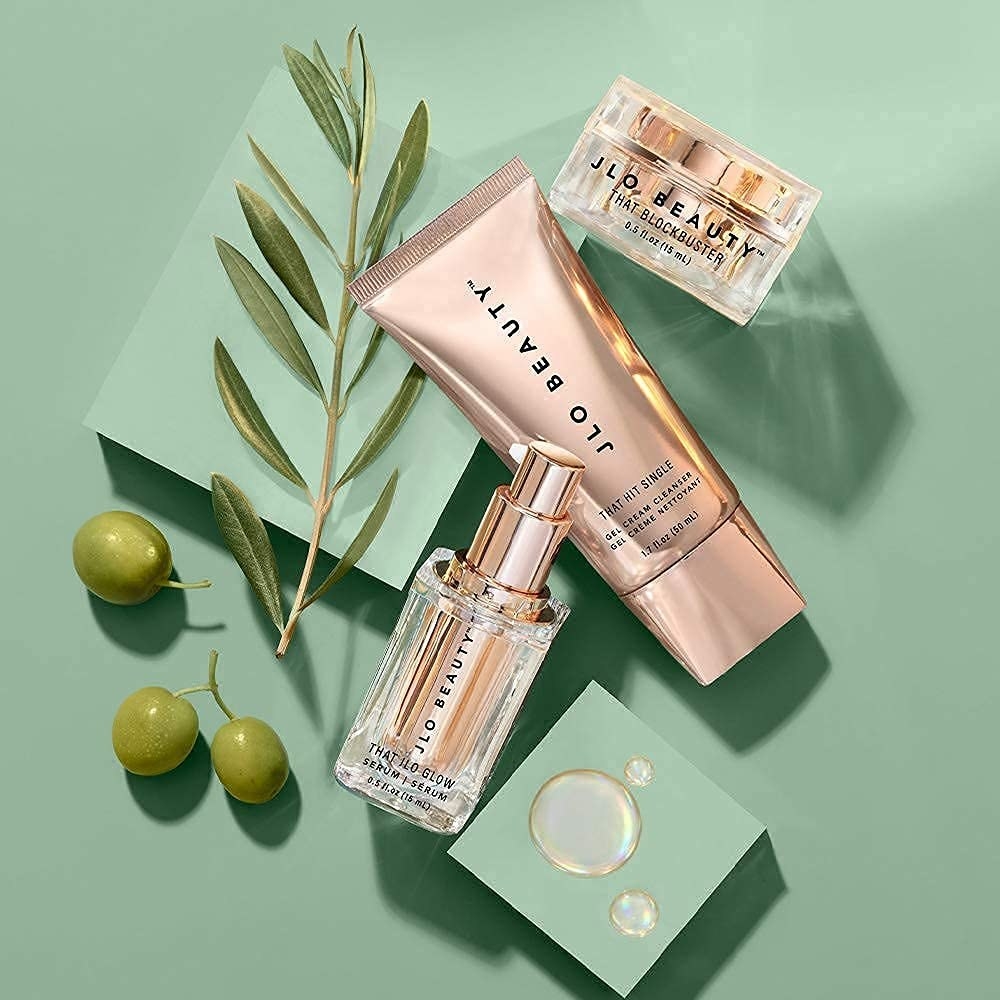 A set of skincare products in gold with green background and olives