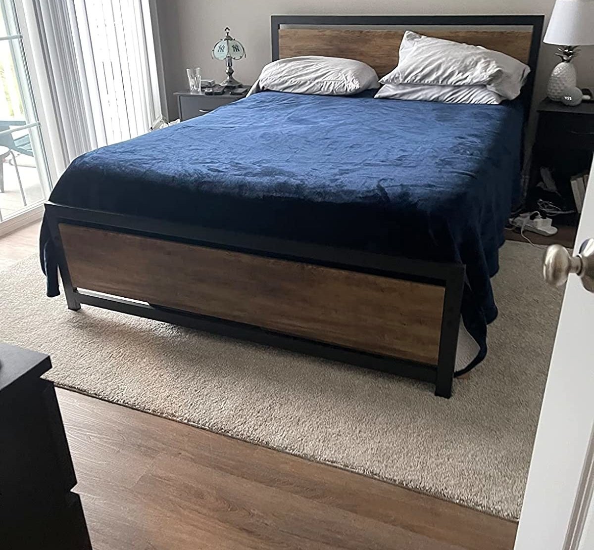 A reviewer&#x27;s photo of the bedframe with a mattress and duvet covers.