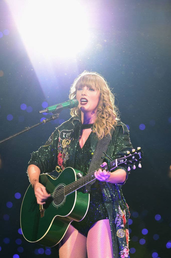 Taylor Swift playing a green guitar.