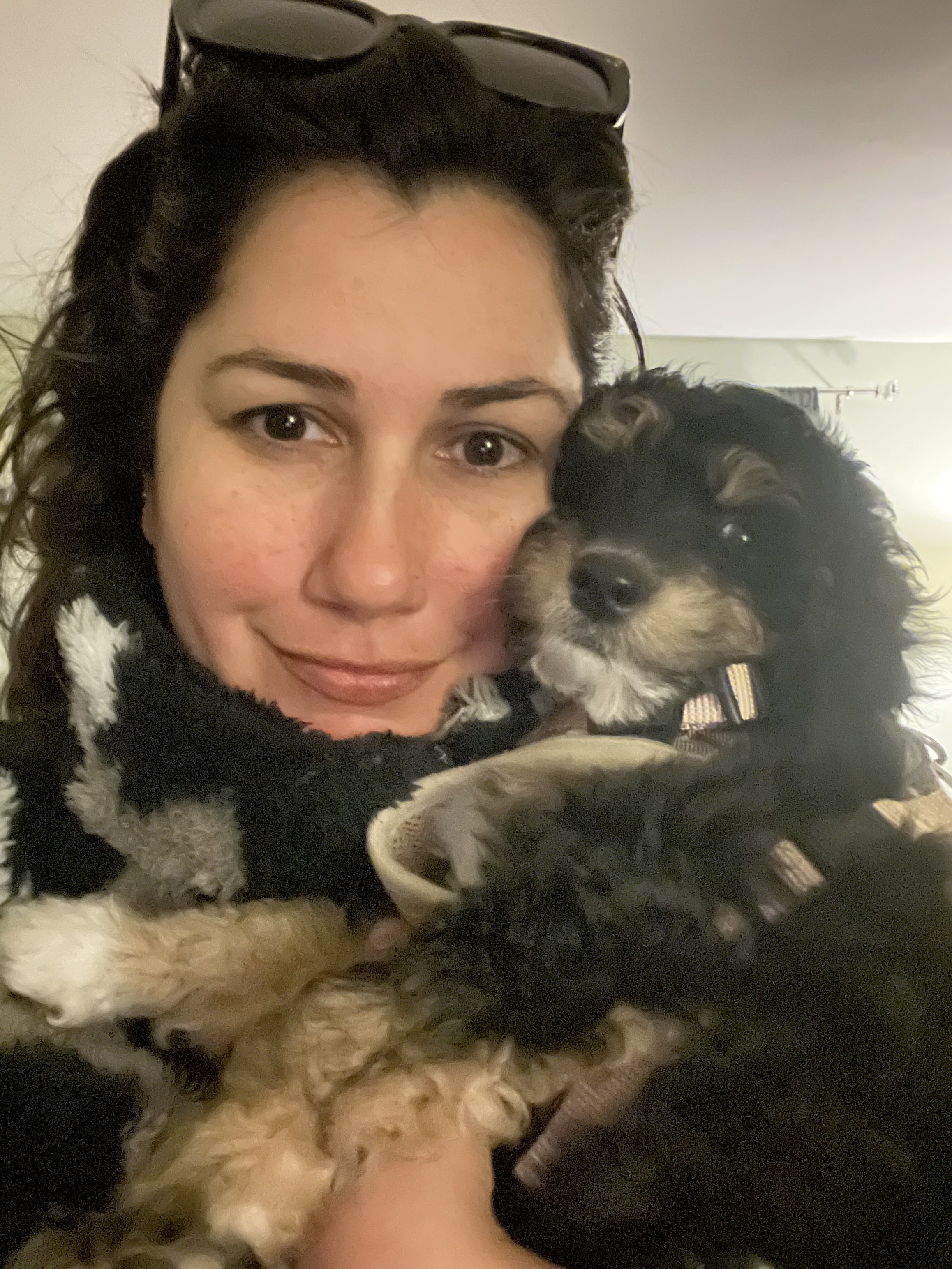 woman holds a small, curly puppy close to her face