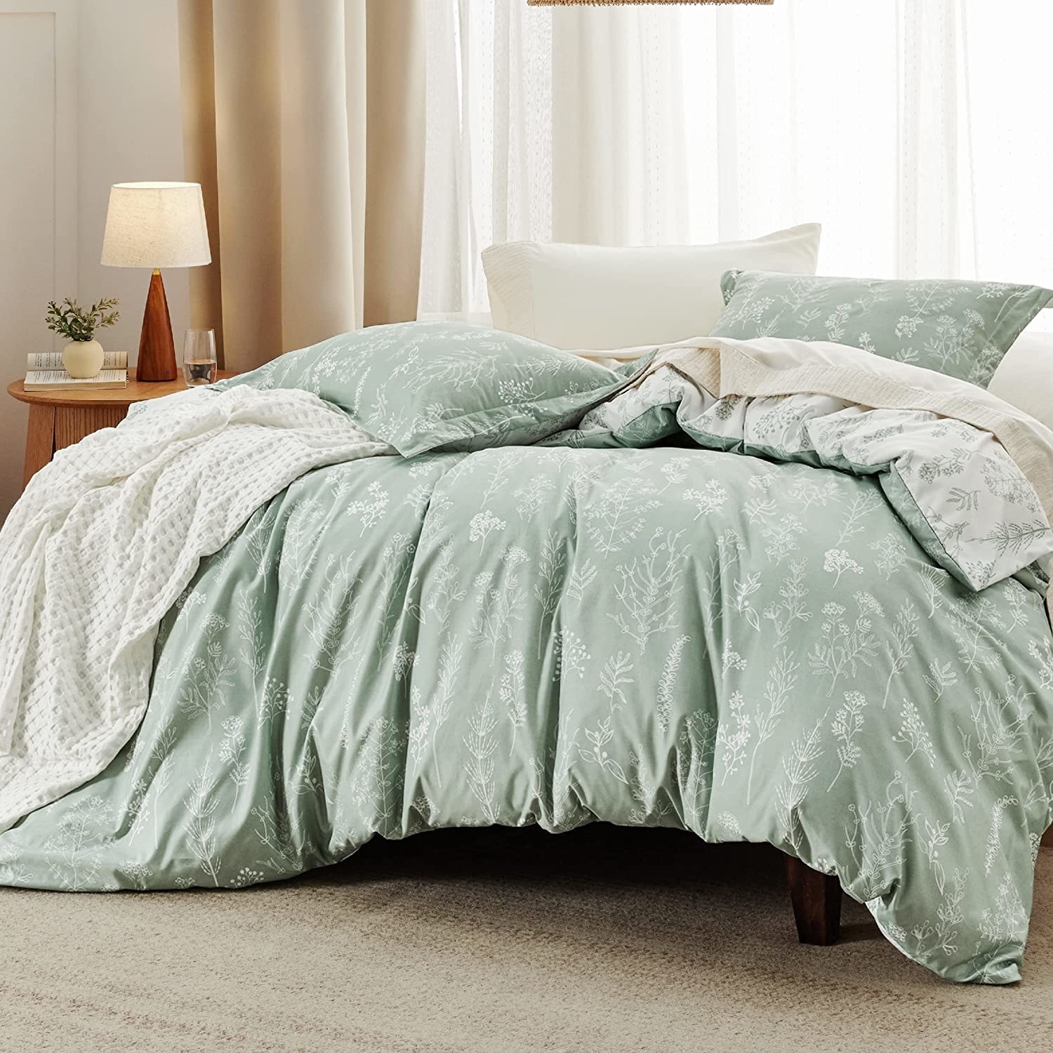 A light green blanket and pillows are shown on a bed in a bedroom