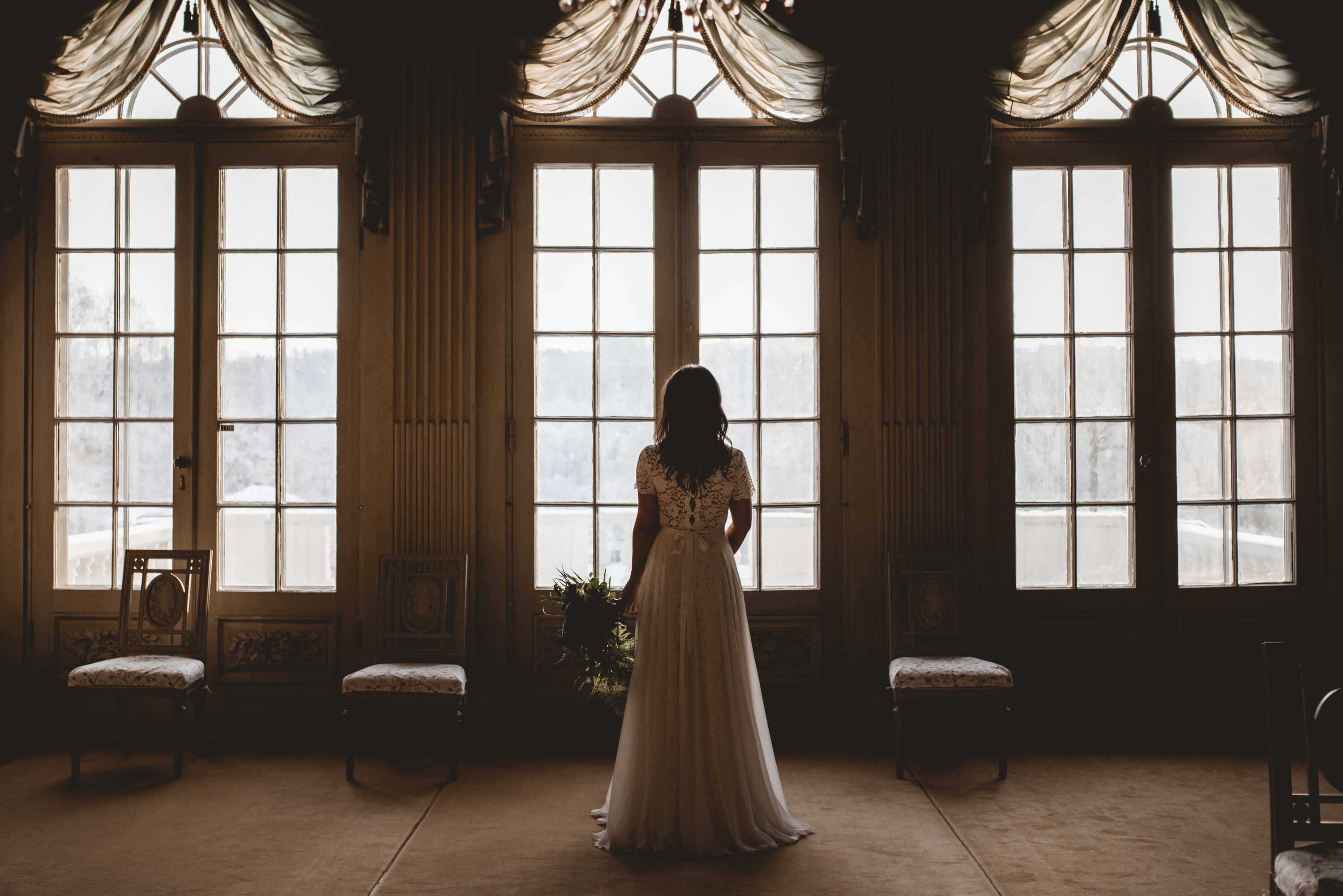 Bride looking out the window while holding her bouquet