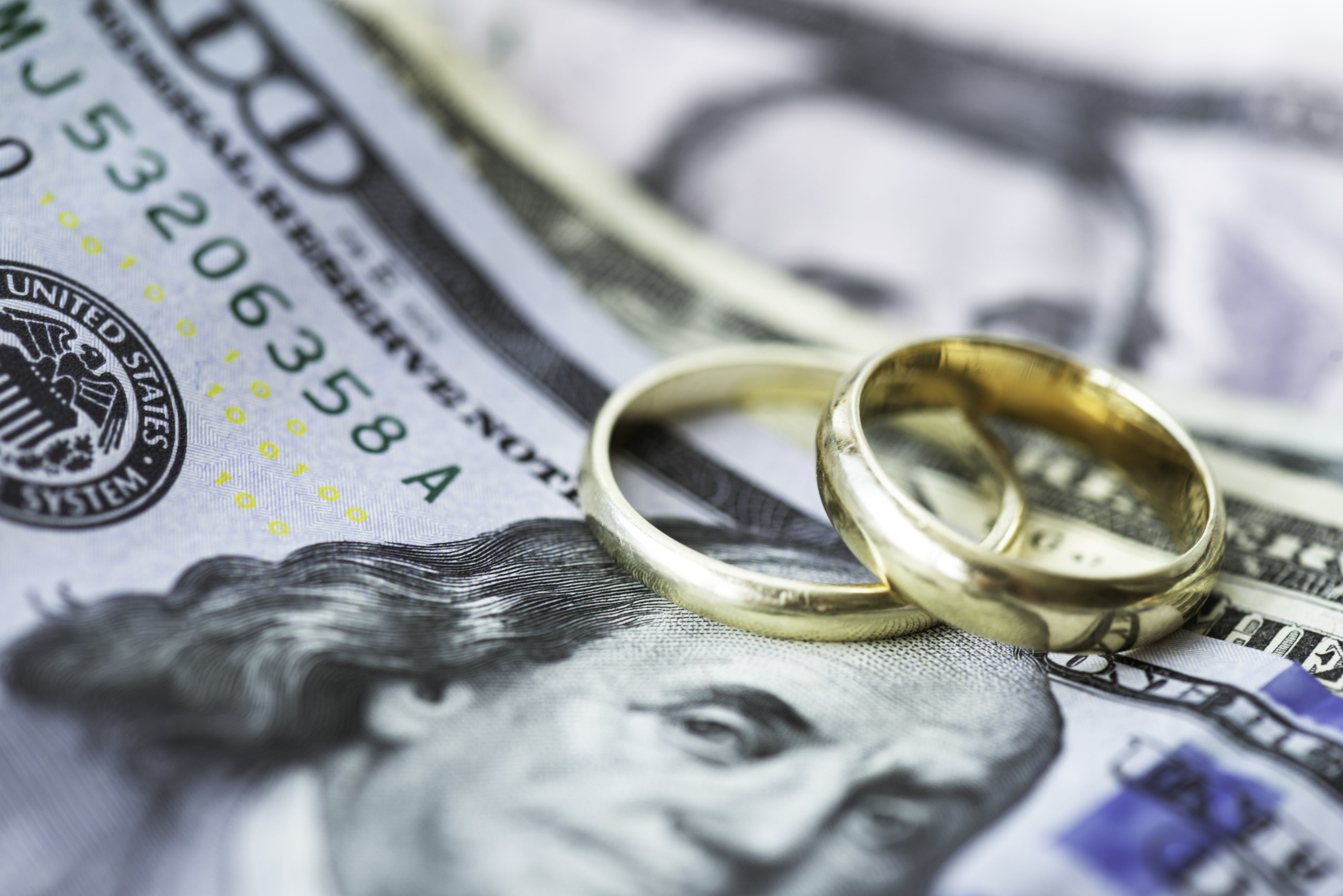 wedding rings sitting on pile of assorted United States bills