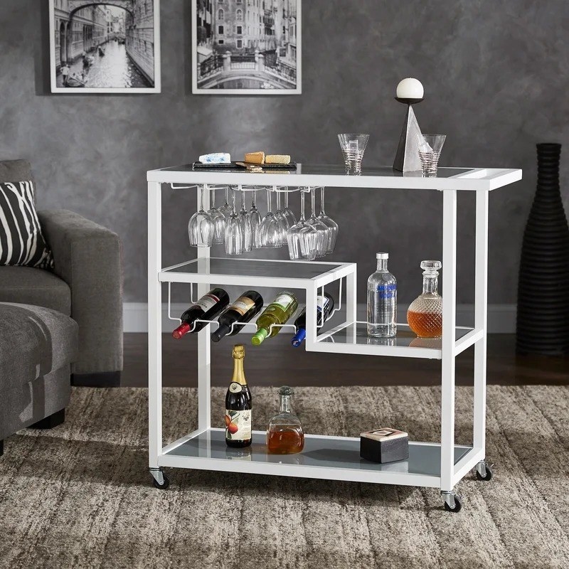 the white bar cart with storage area for wine bottles and shelves for other barware