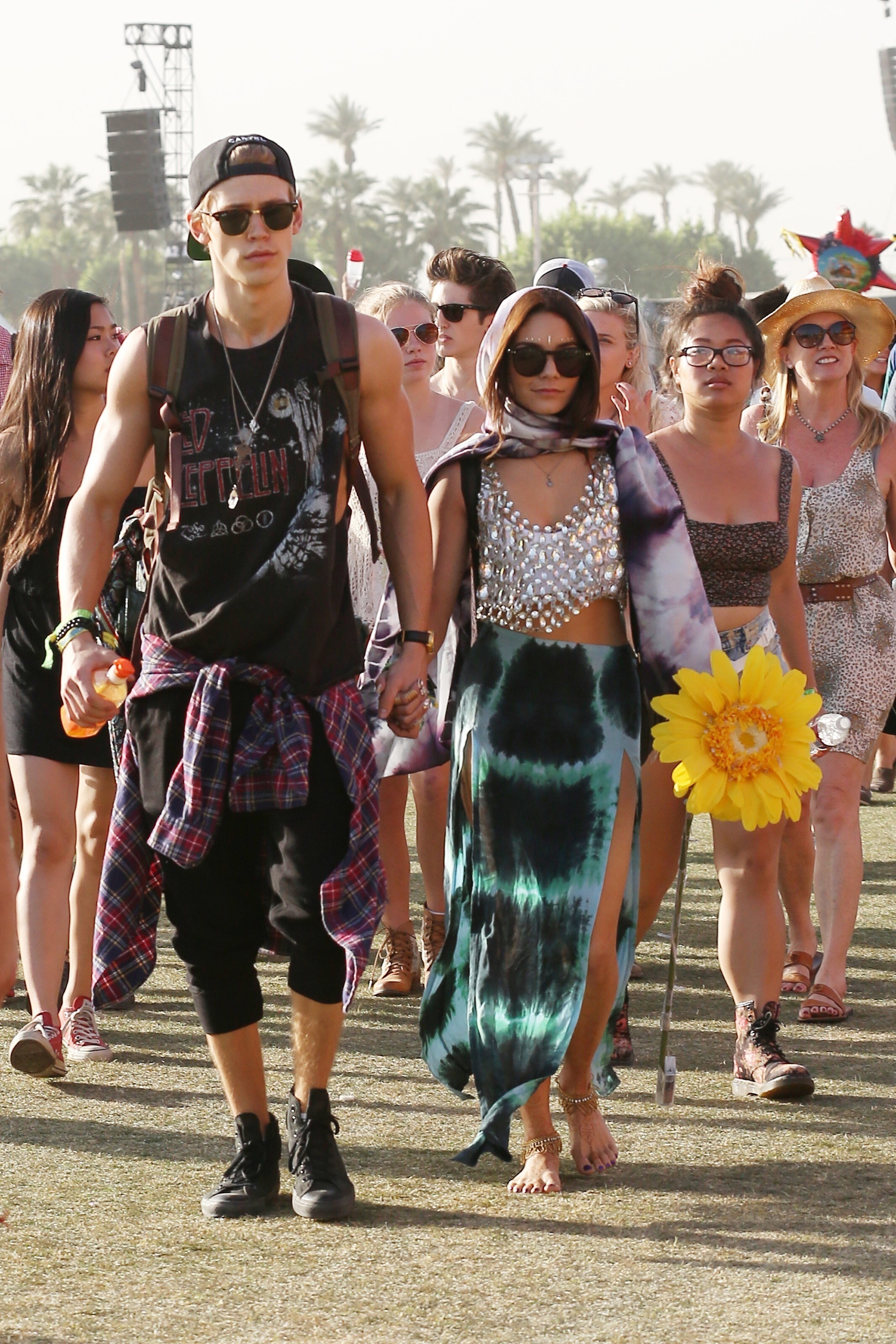 Austin Butler and Vanessa Hudgens holding hands at an outdoor festival