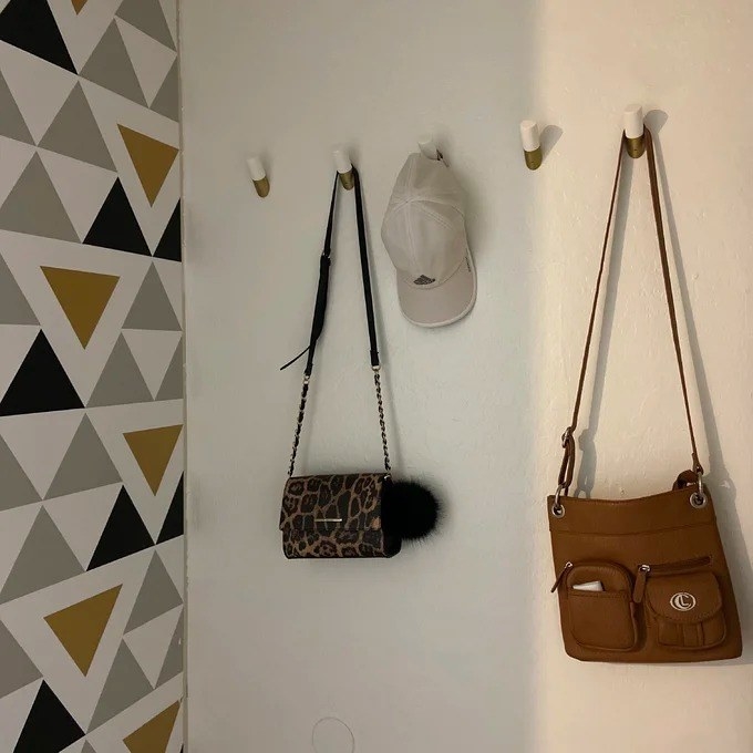 gold-tone and white wall hooks with two purses on wall
