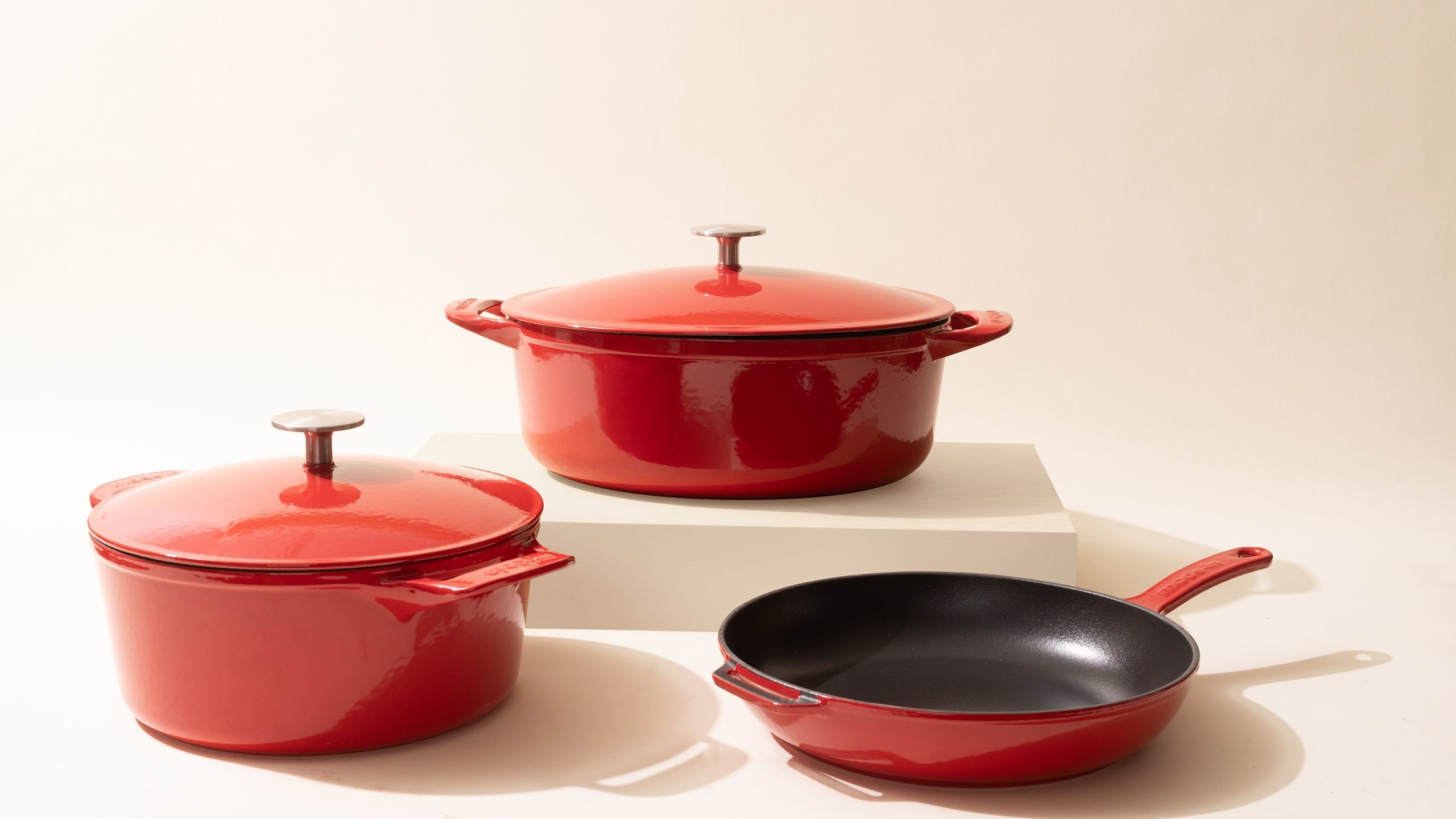 a set of three red enamel cookware pieces