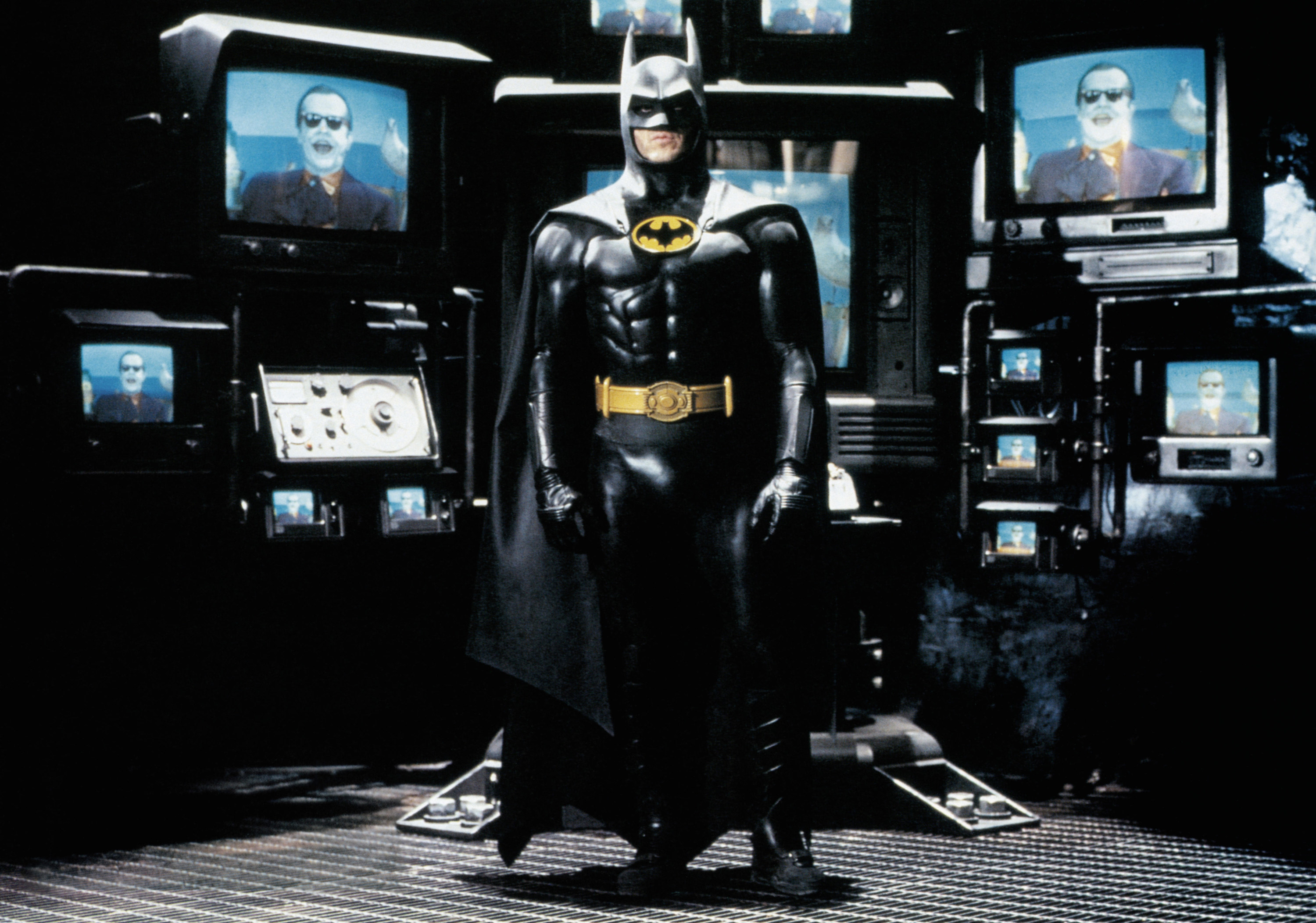 Batman stares near multiple television monitors featuring the Joker