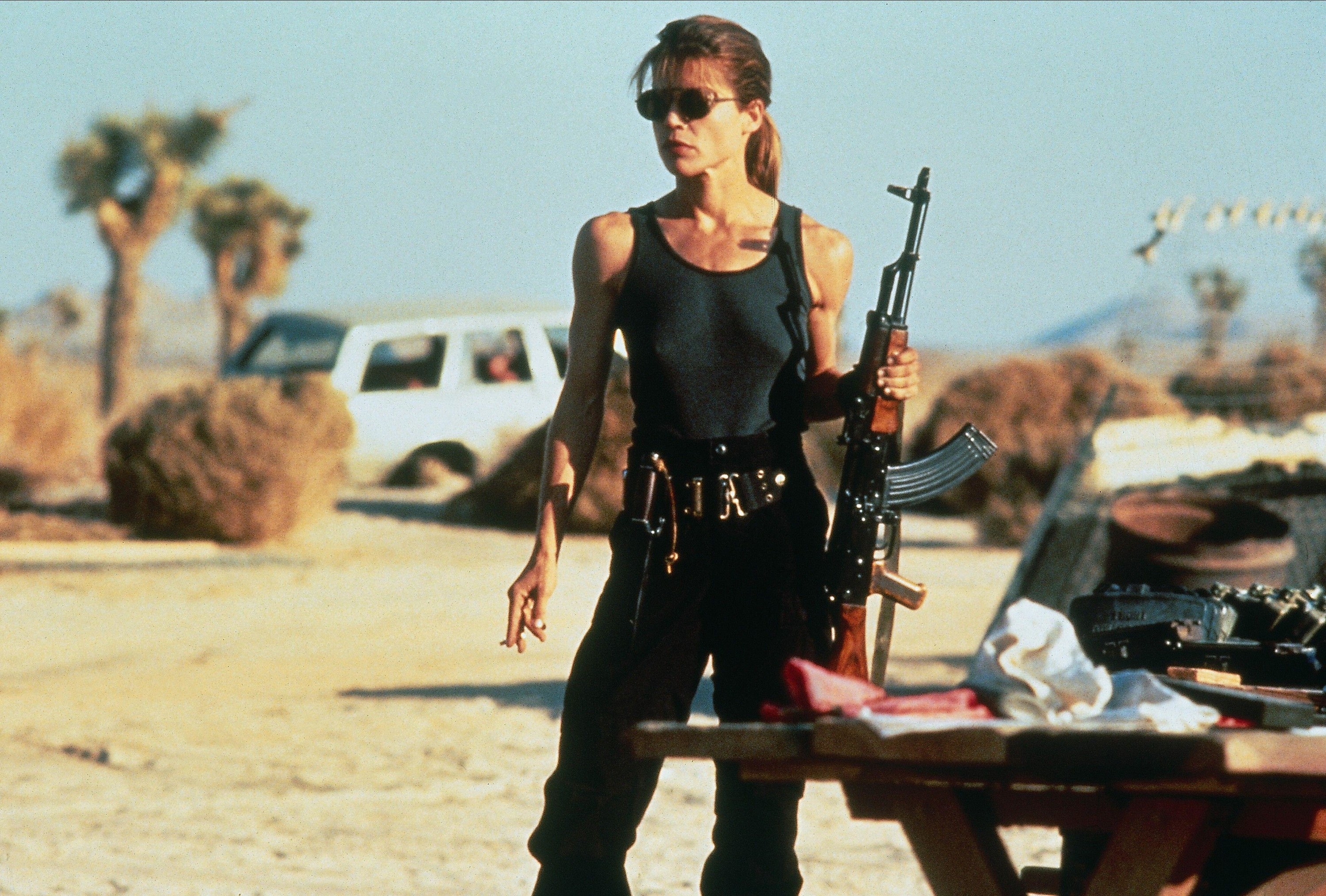 Linda Hamilton holds an assault rifle in a barren desert