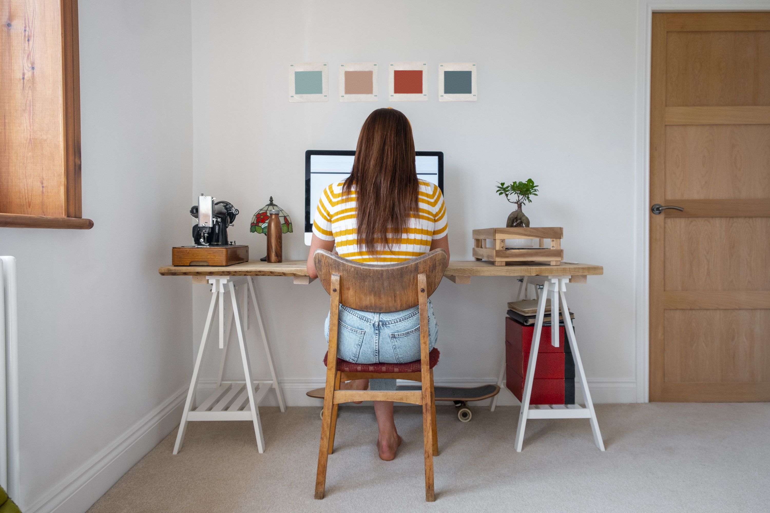 A woman sits at her home desk and works on her computer