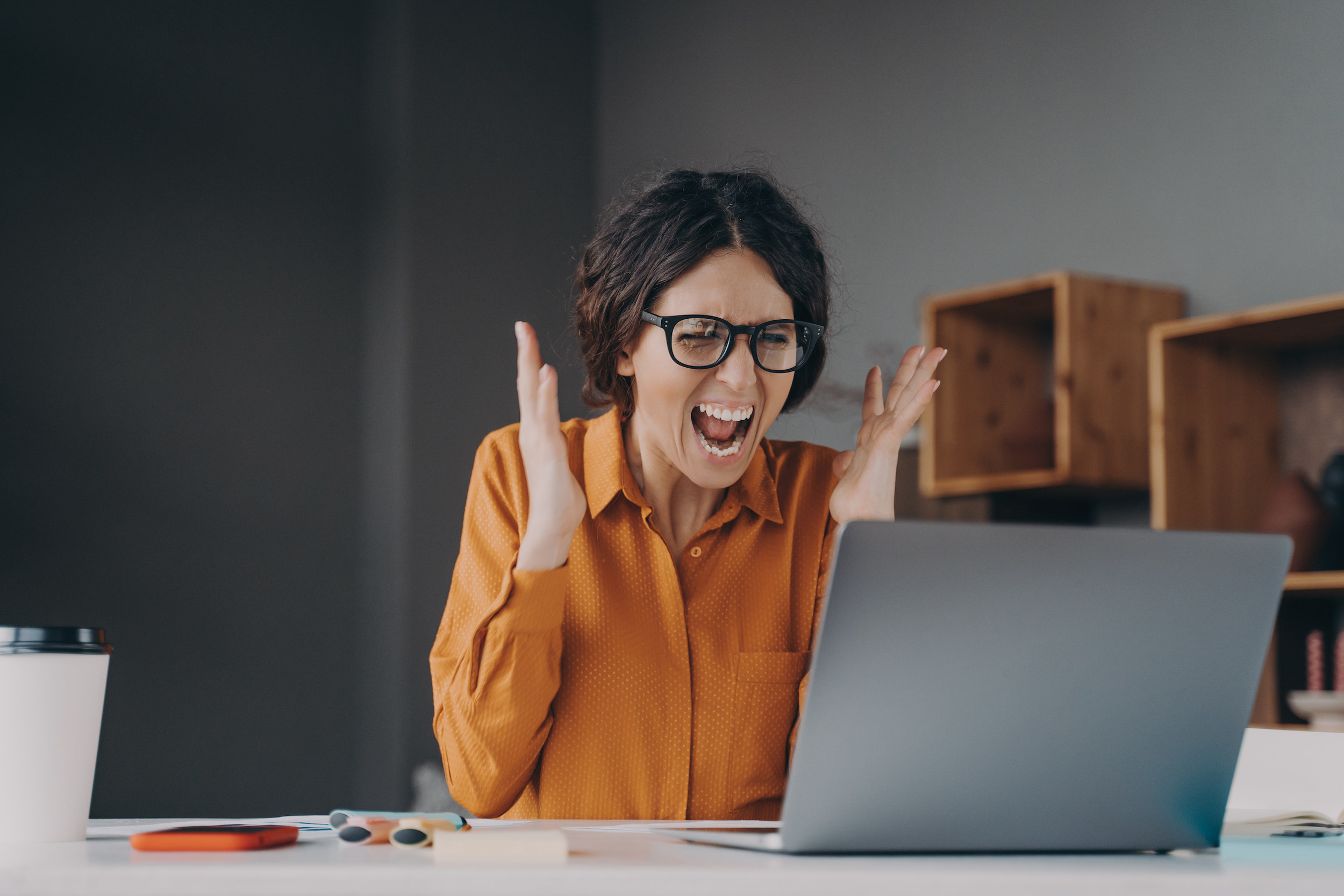 A woman screaming in front of her laptop