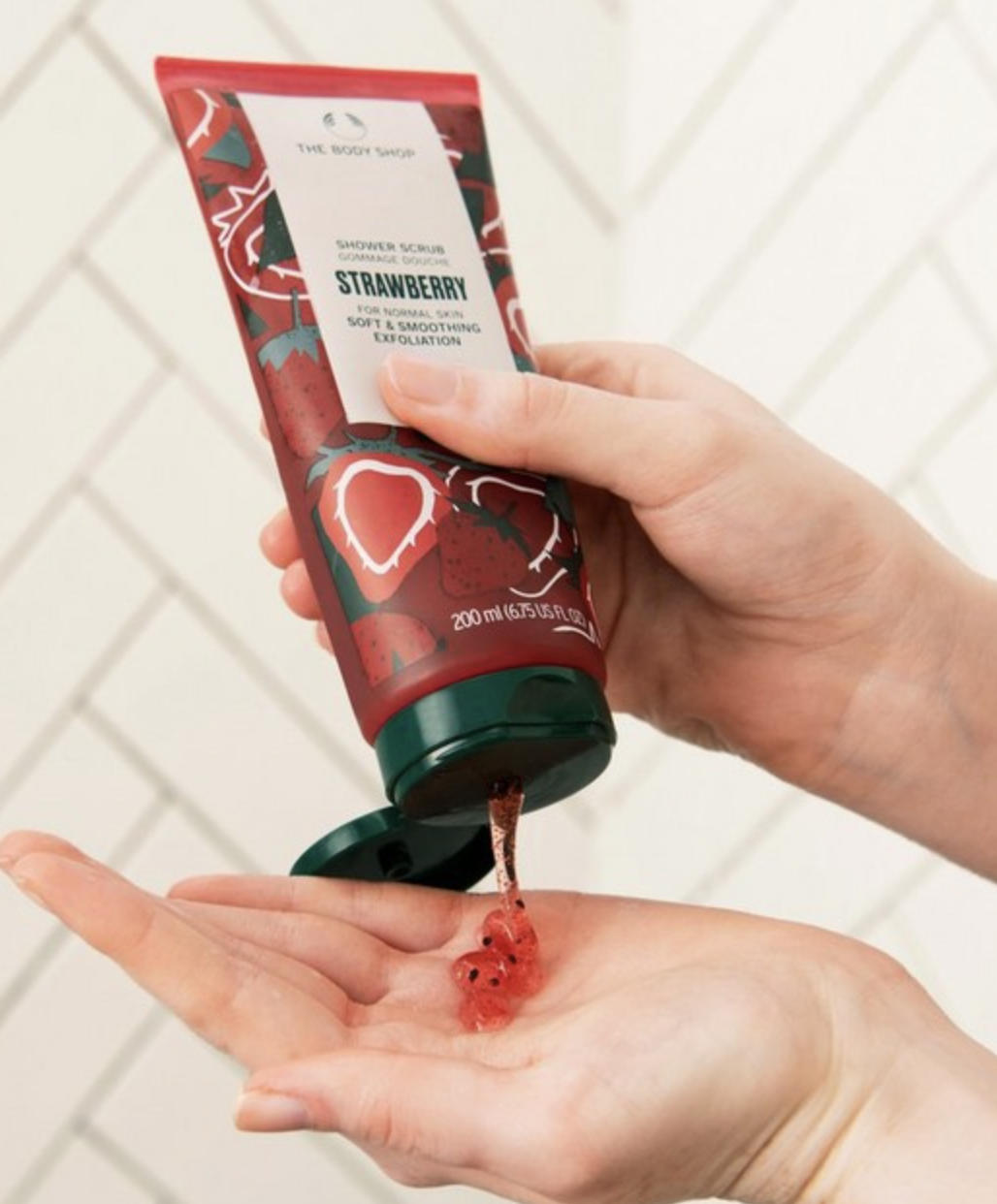 a person squeezing the tube of body scrub into their hand in the shower