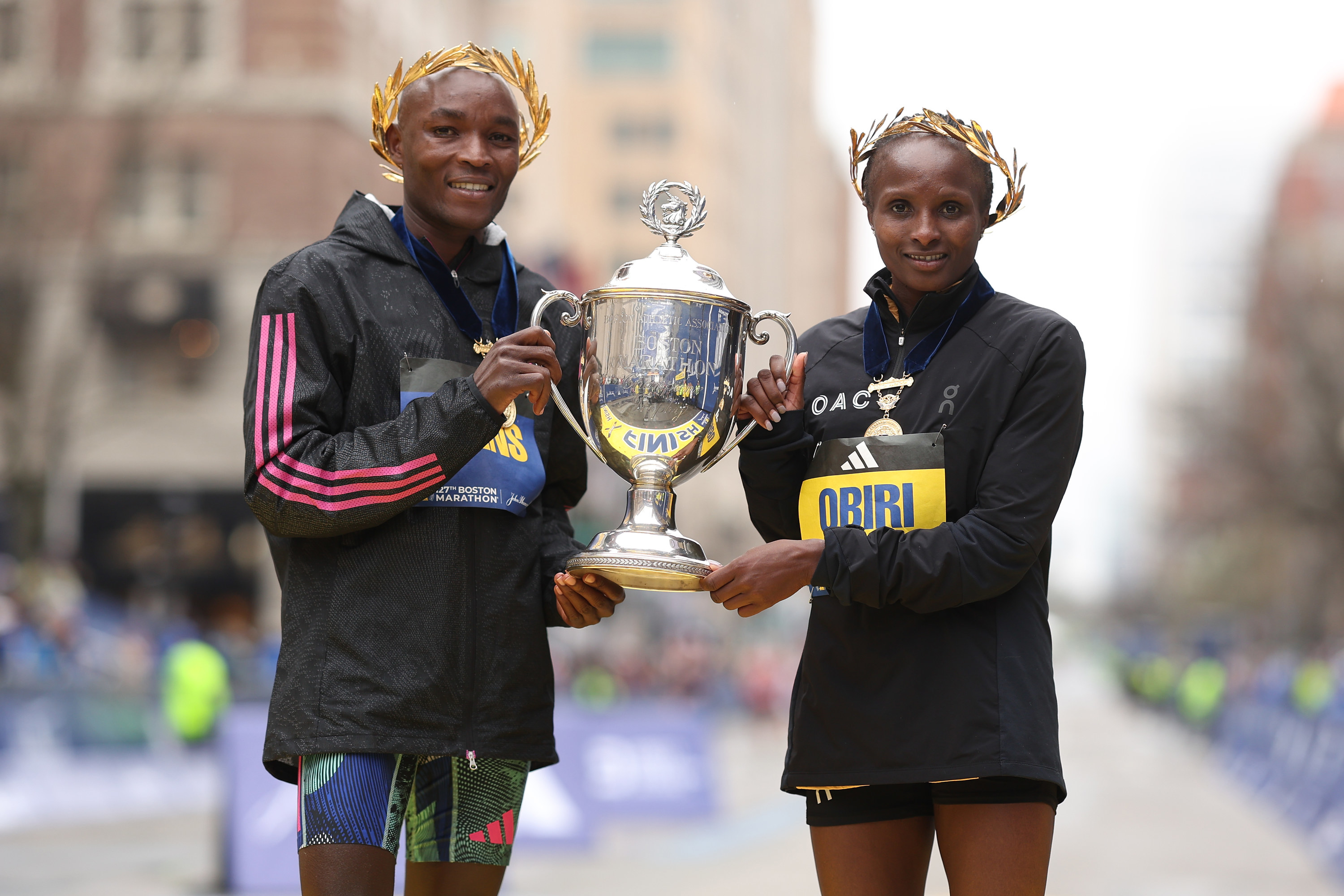 Evans Chebet of Kenya (L) and Hellen Obiri of Kenya (R) pose with the trophy on the finish line.