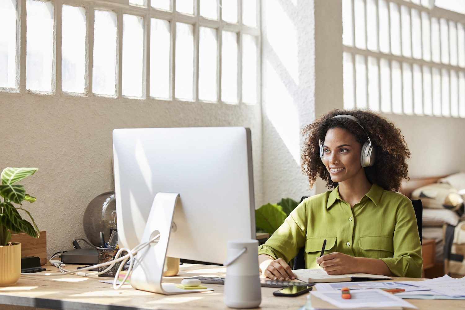 A woman with headphones on in front of her computer