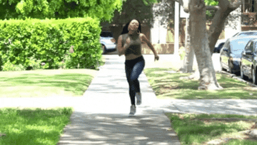 A gif of a woman happily skipping fown the street