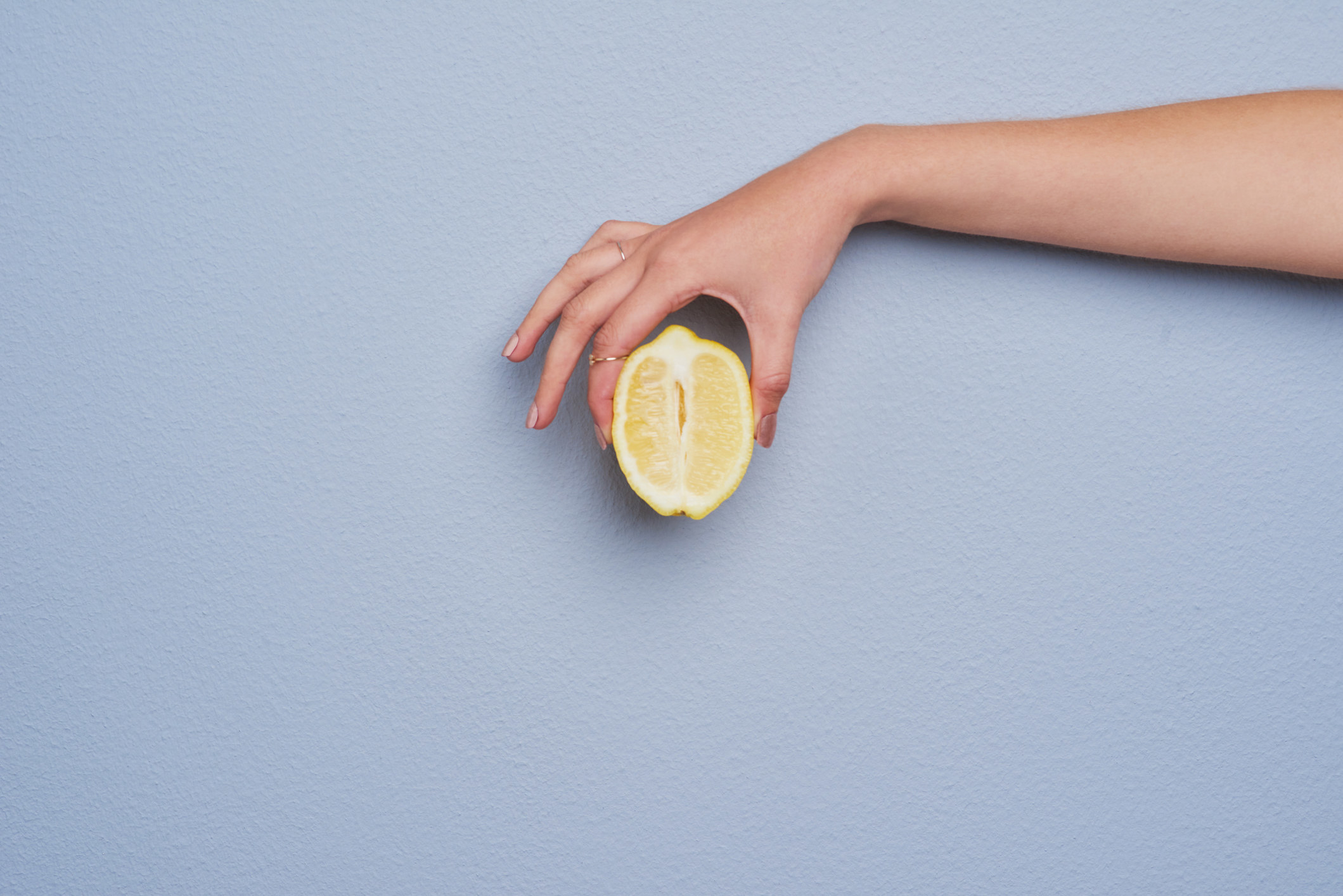 Cropped studio shot of an unrecognizable woman holding a lemon against gray background