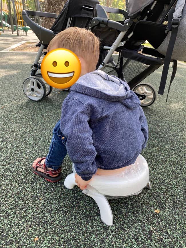 reviewer's child using portable potty in a park