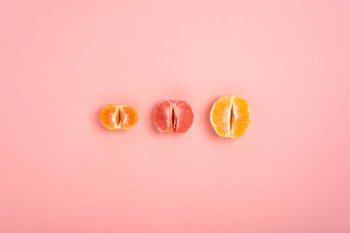 tangerine, grapefruit and orange cut in half on a peach background as a symbol of the vagina and female fertility, no people