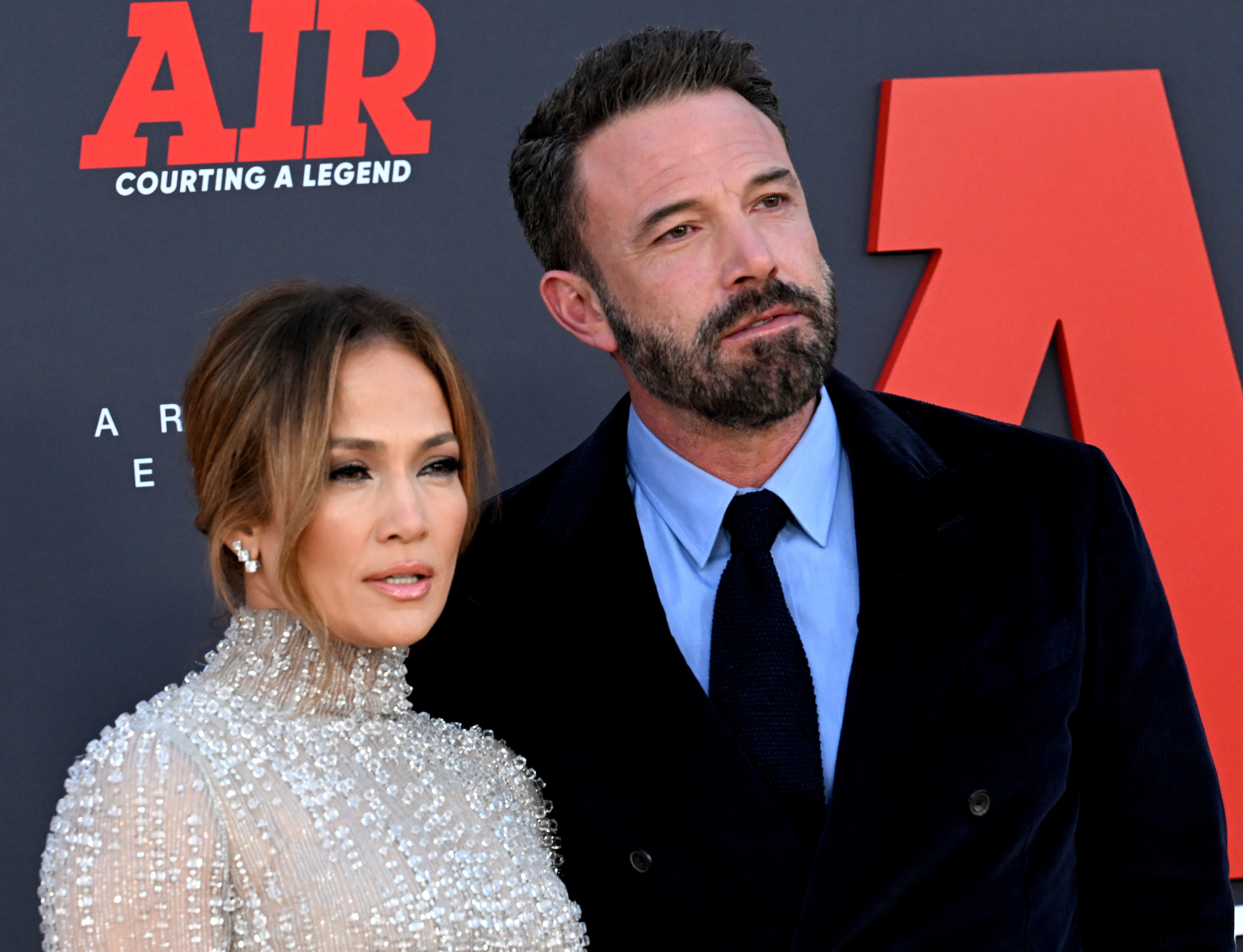 Jennifer Lopez in a beaded gown posing with Ben Affleck in suit on the red carpet for the Air movie premiere