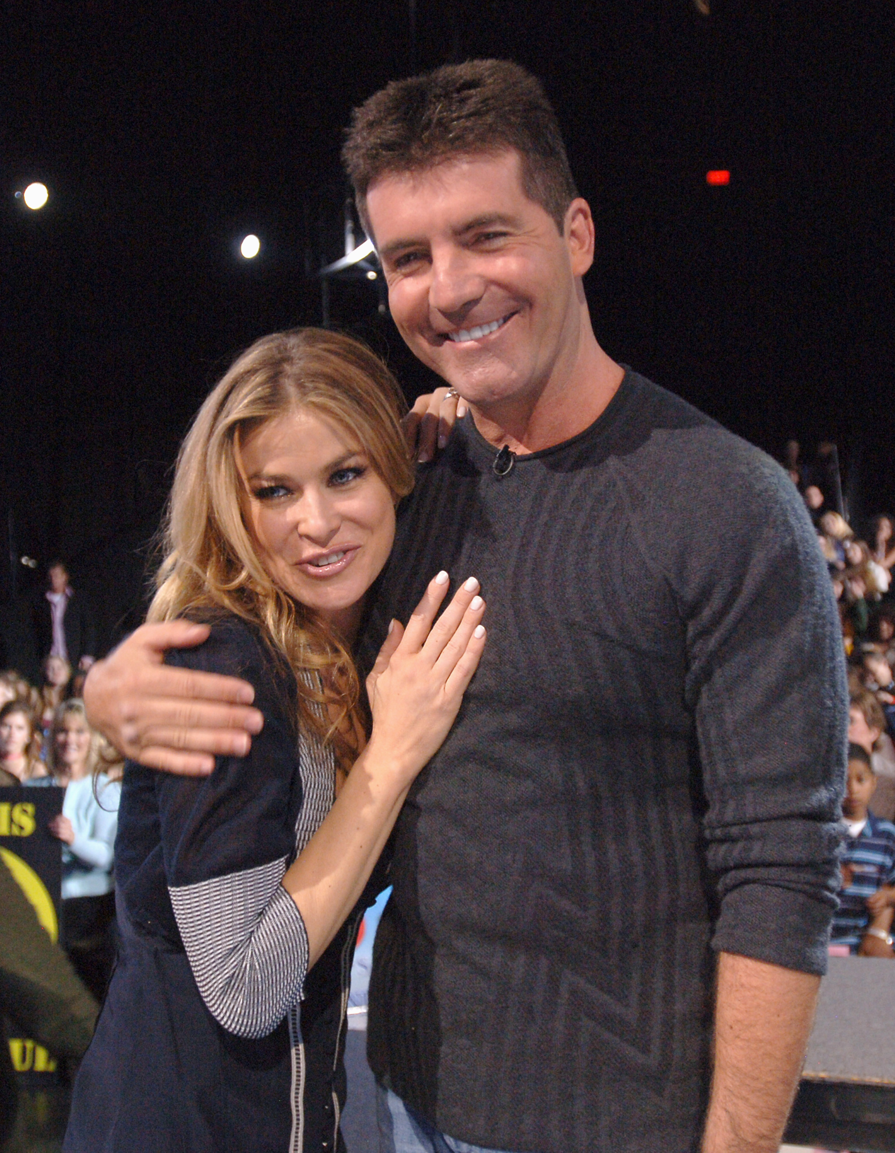 Carmen Electra and Simon Cowell cuddling while standing in front of the Idol audience