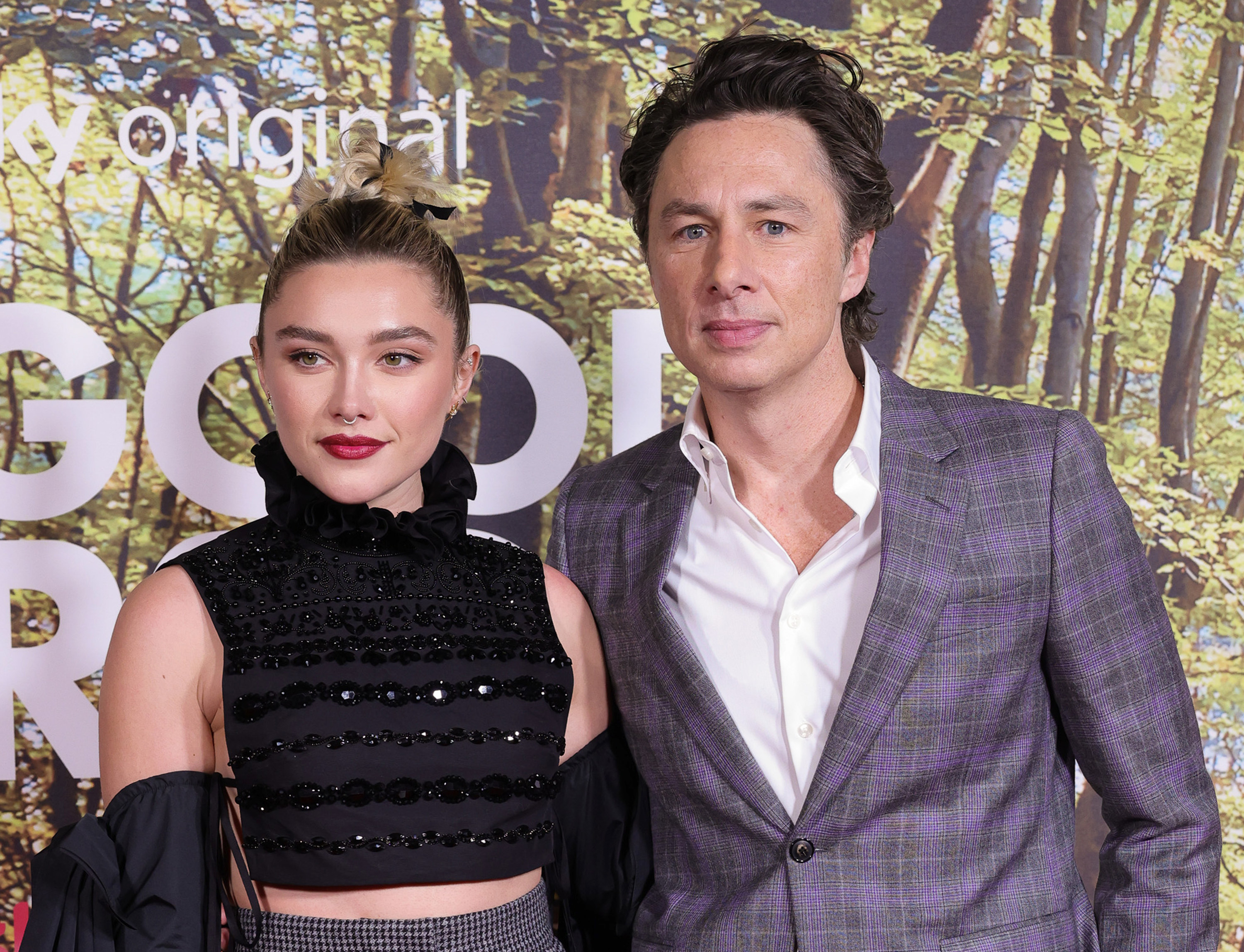 Zach Braff and Florence Pugh posing together on the red carpet, she&#x27;s wearing a black crop top and high-waisted pants, he&#x27;s in a purple plaid suit