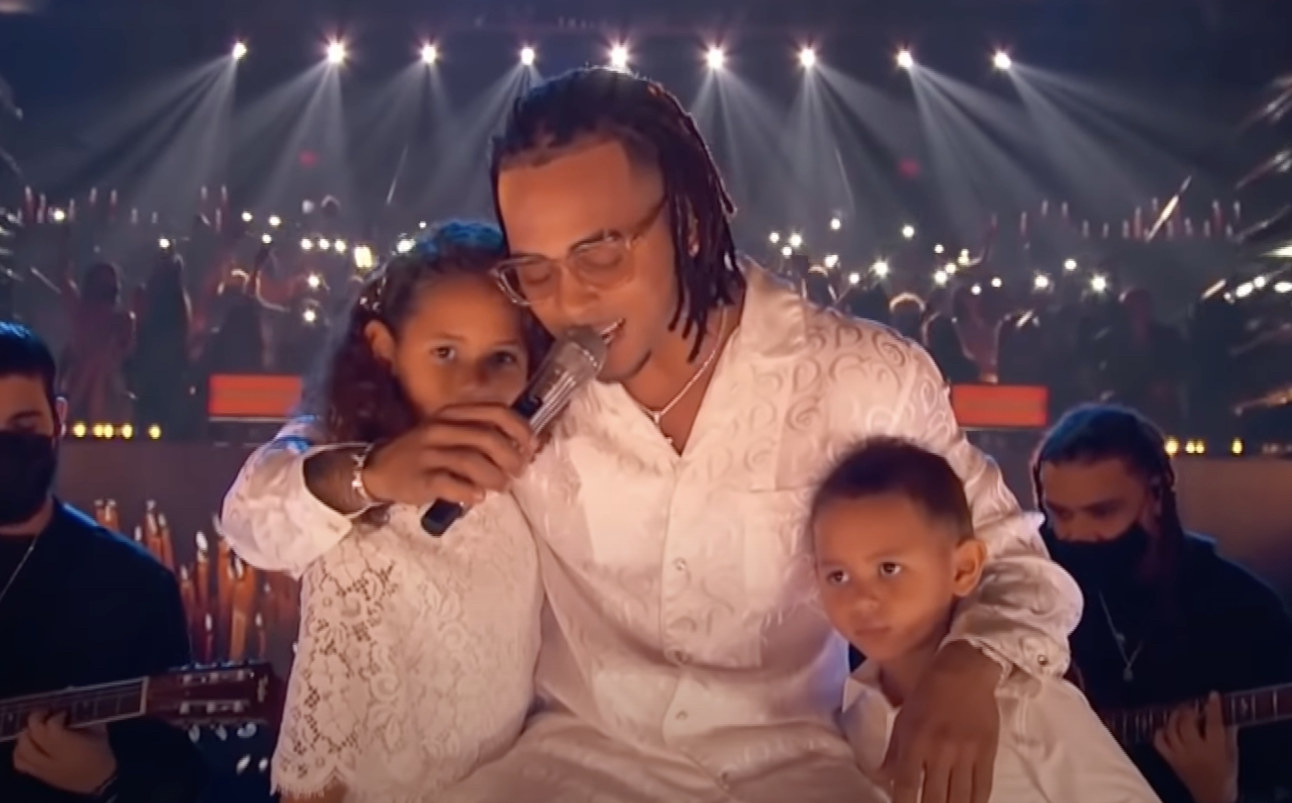 Ozuna singing on stage with his two children