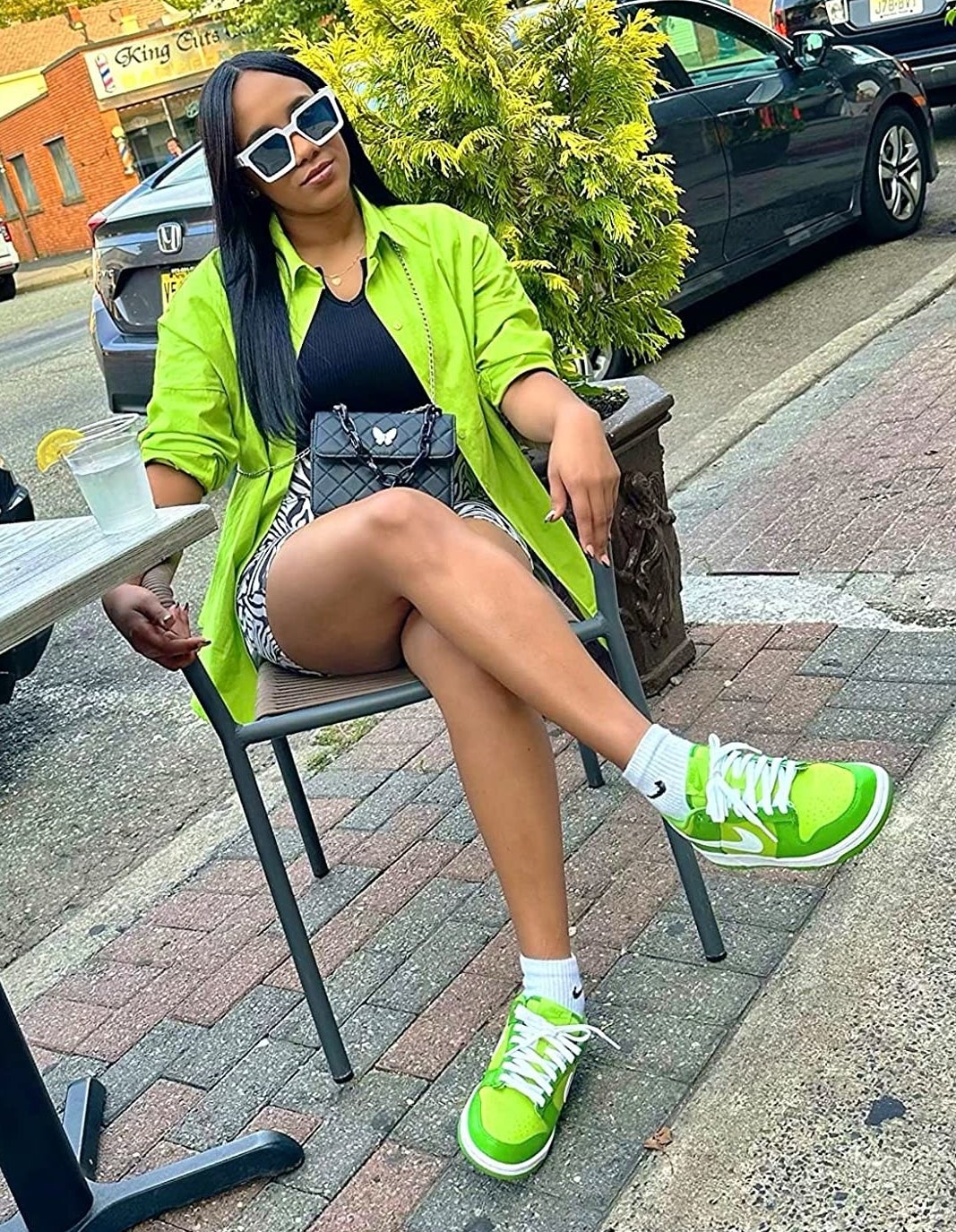 Reviewer wearing lime green button down blouse over black shirt, with matching sneakers