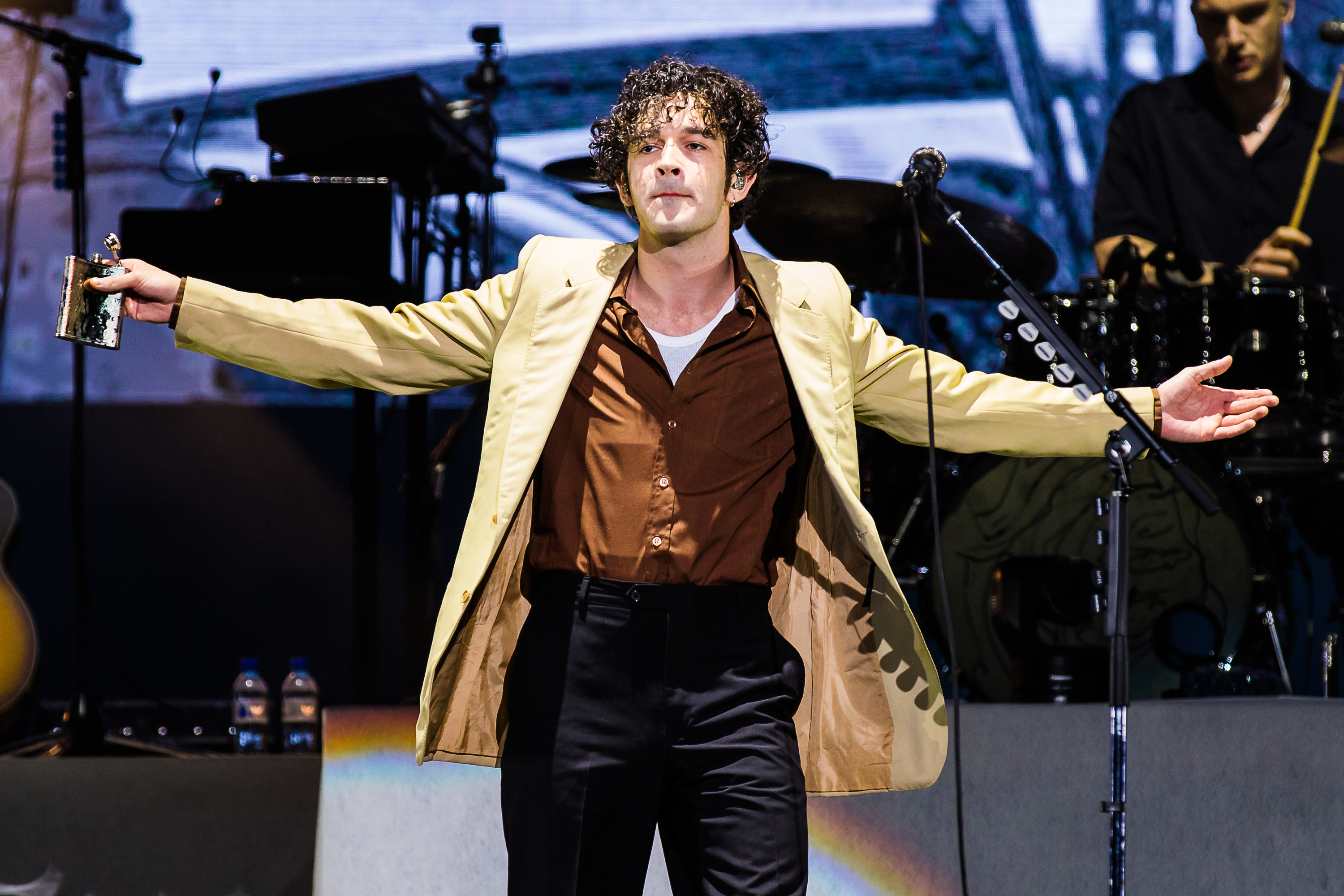 Matt Healy performing and drinking alcohol on stage during a tour