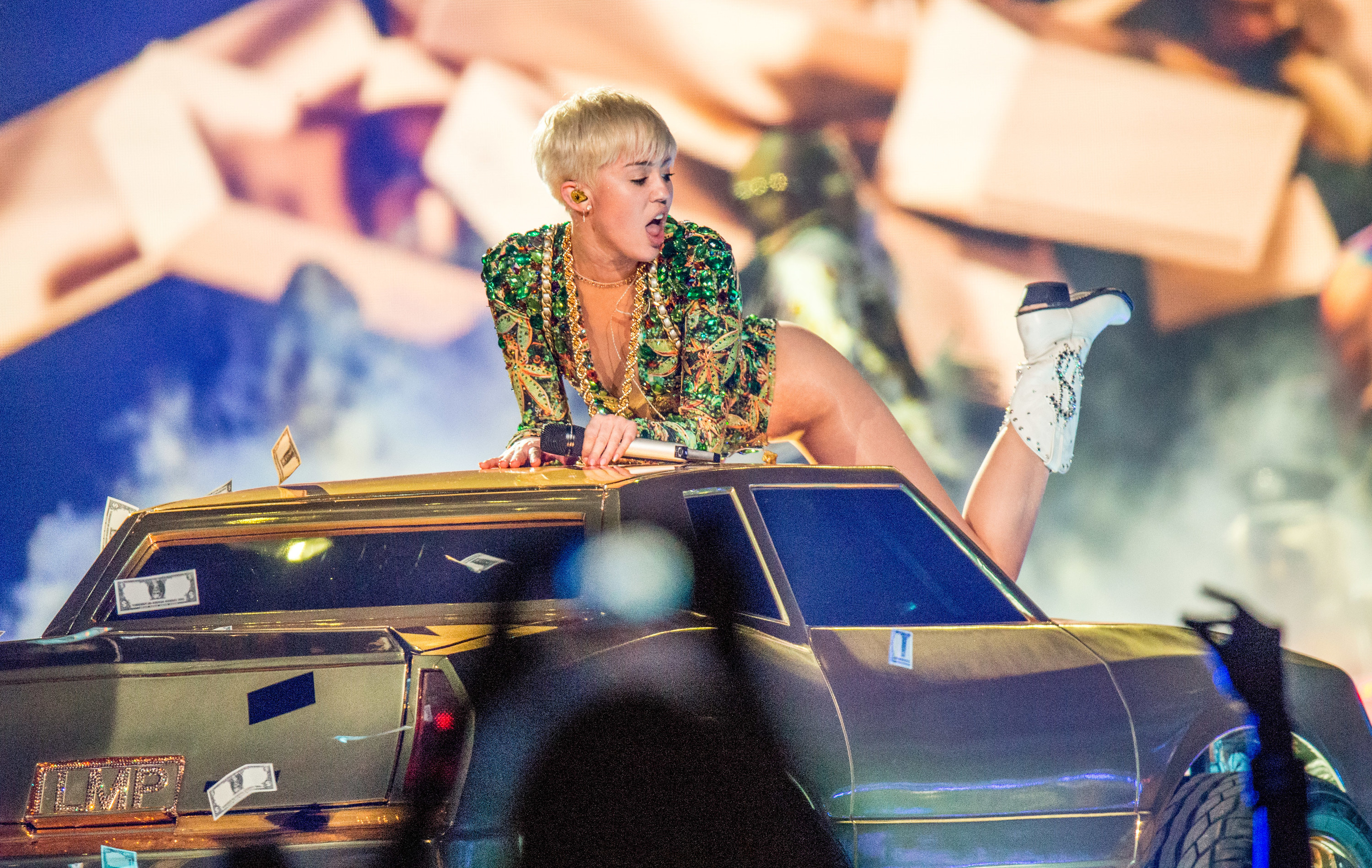 Miles Cyrus on top of a gold car on her Bangerz Tour