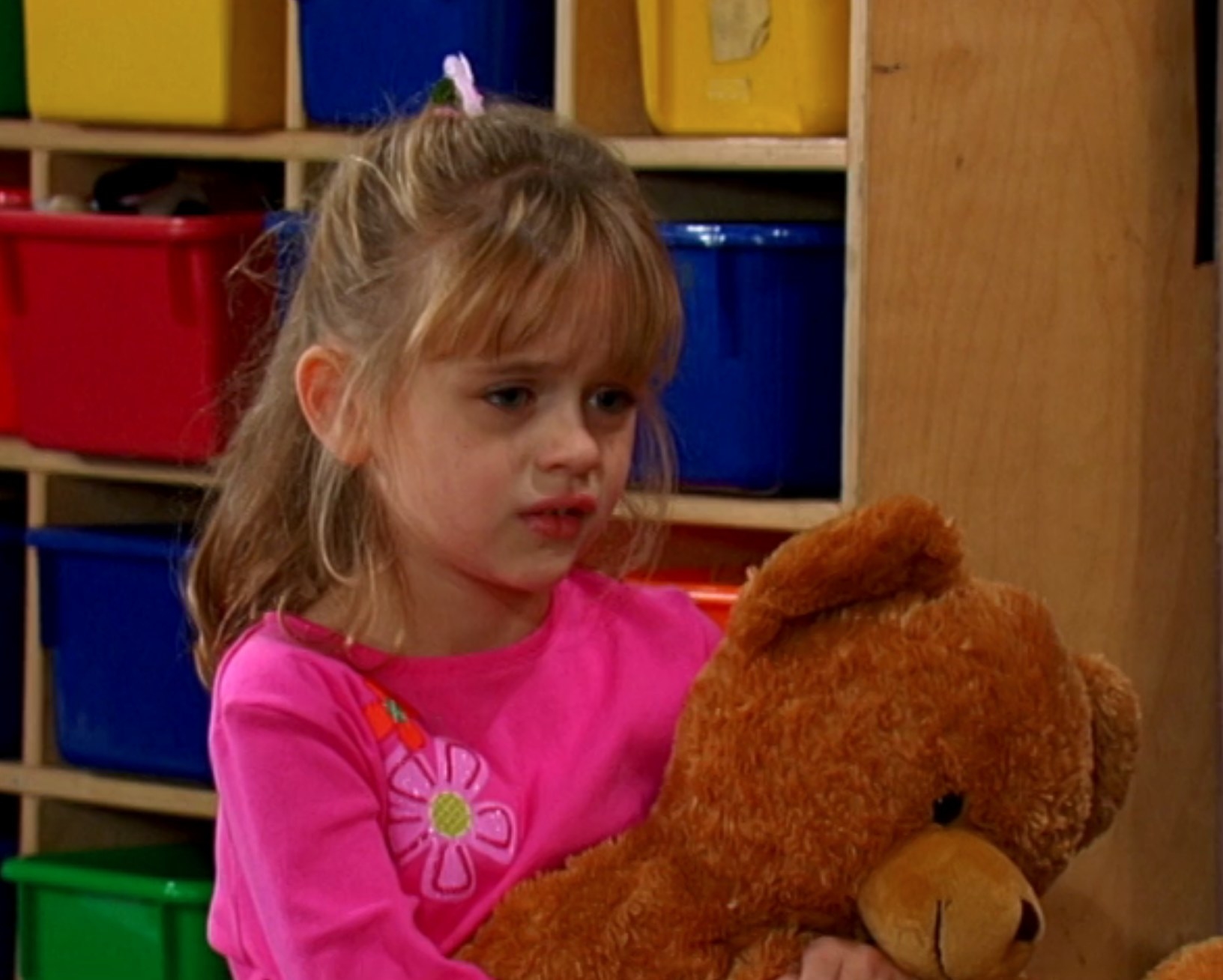 Joey King as Emily holds a teddy bear while attending the Tipton Hotel day care