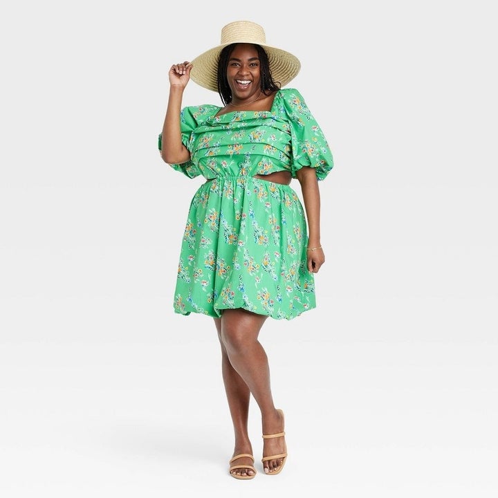 A model in a green bubble hem mini with a floral print and side cutouts